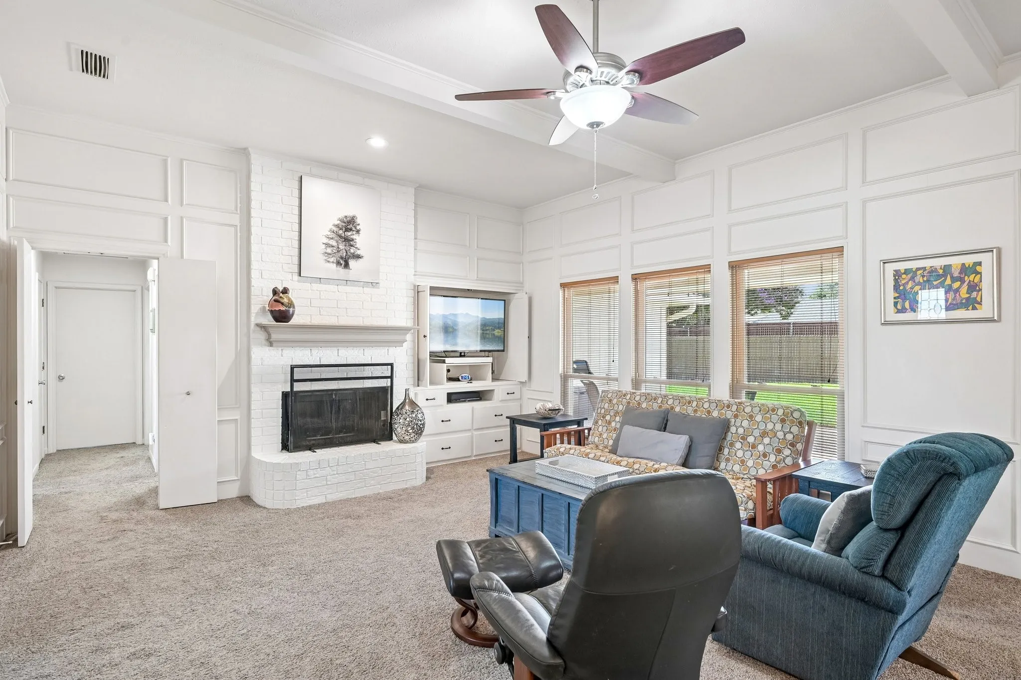Living area featuring white brick fireplace, built-in entertainment console, coffered ceiling, and multiple windows