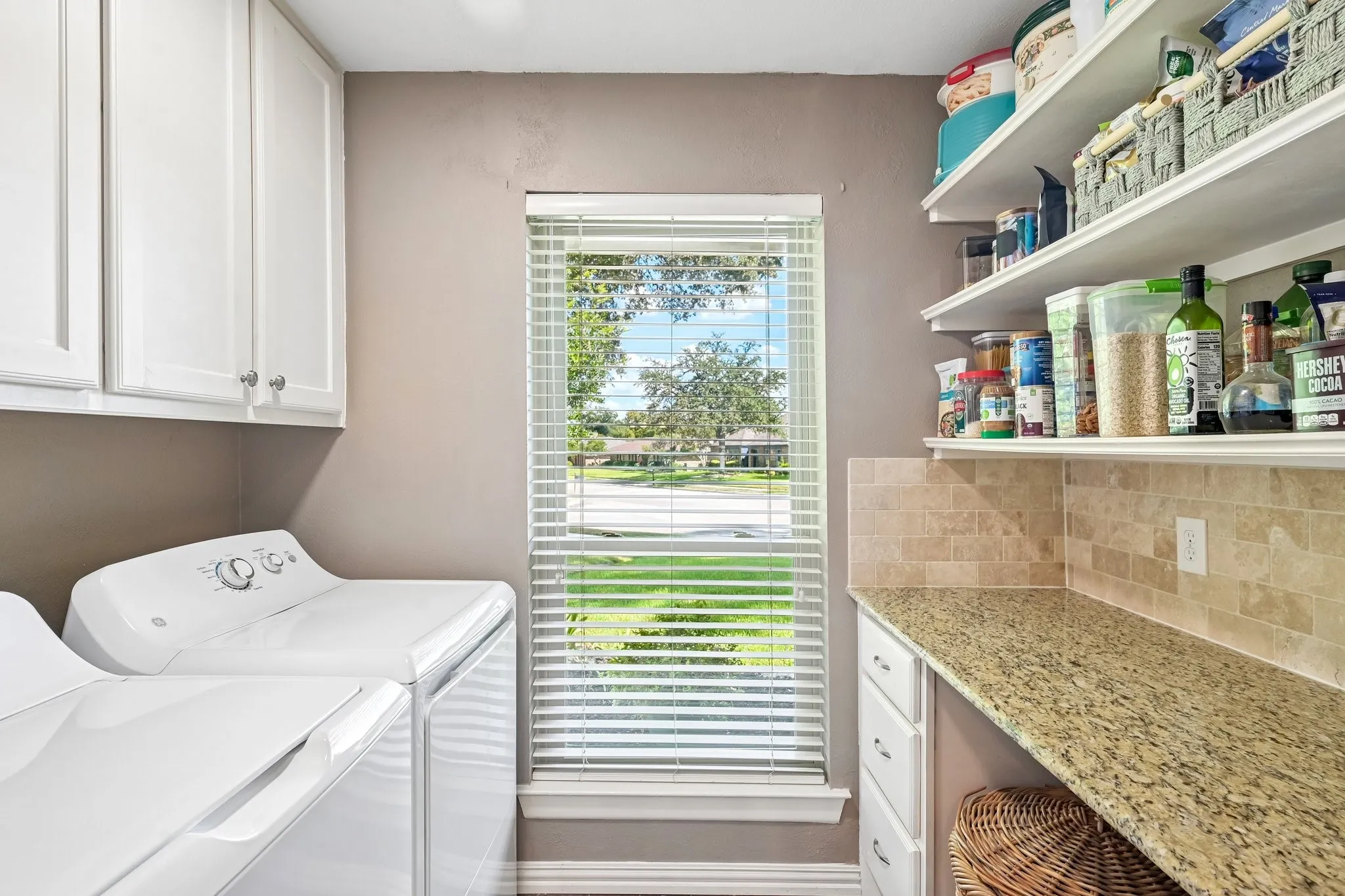 Built-in white cabinetry, granite-finish countertop, tiled backsplash, and open shelving