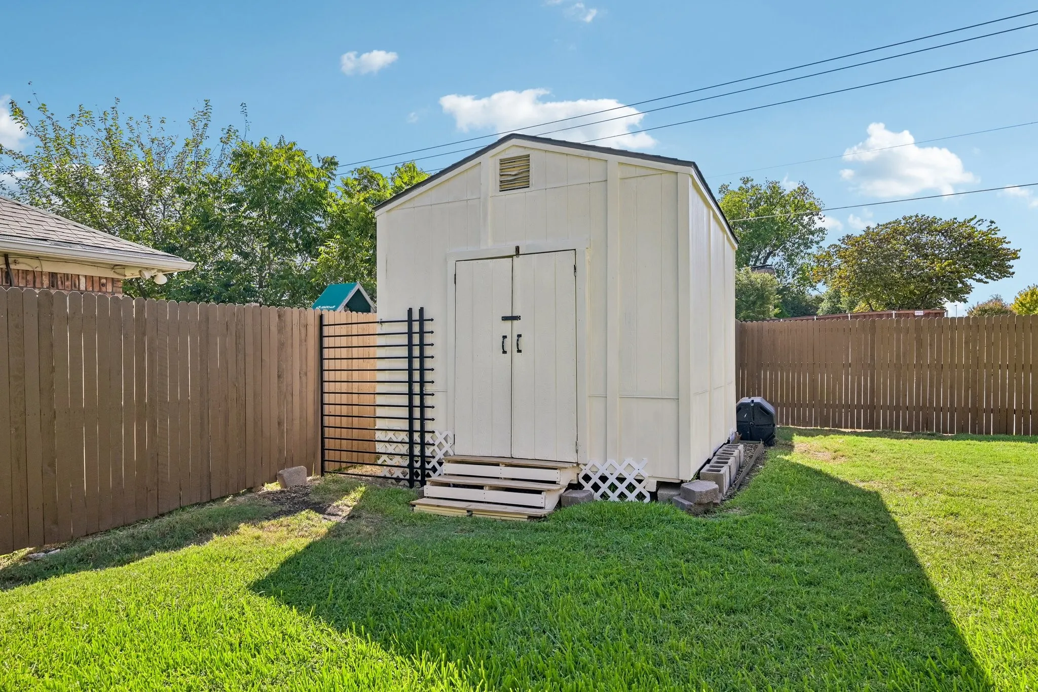 Backyard featuring a detached storage shed with double doors, wood fencing, and a grassy lawn