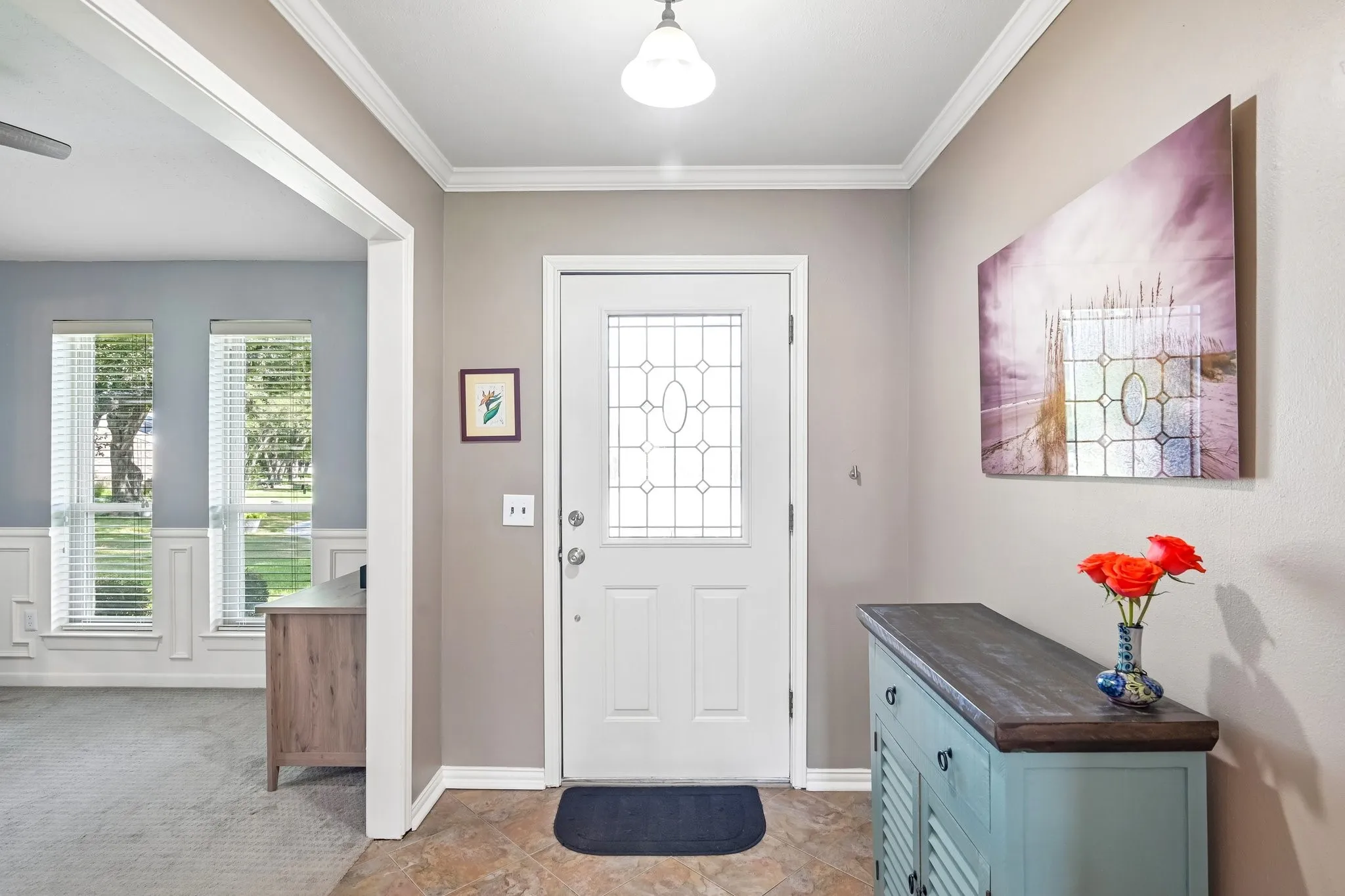 Entryway featuring decorative glass paneled front door, crown molding, and tiled flooring