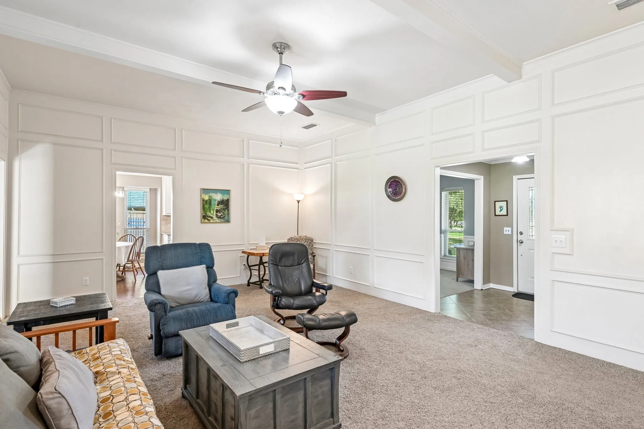 Coffered ceiling detail, decorative wall molding, ceiling fan, and carpet flooring