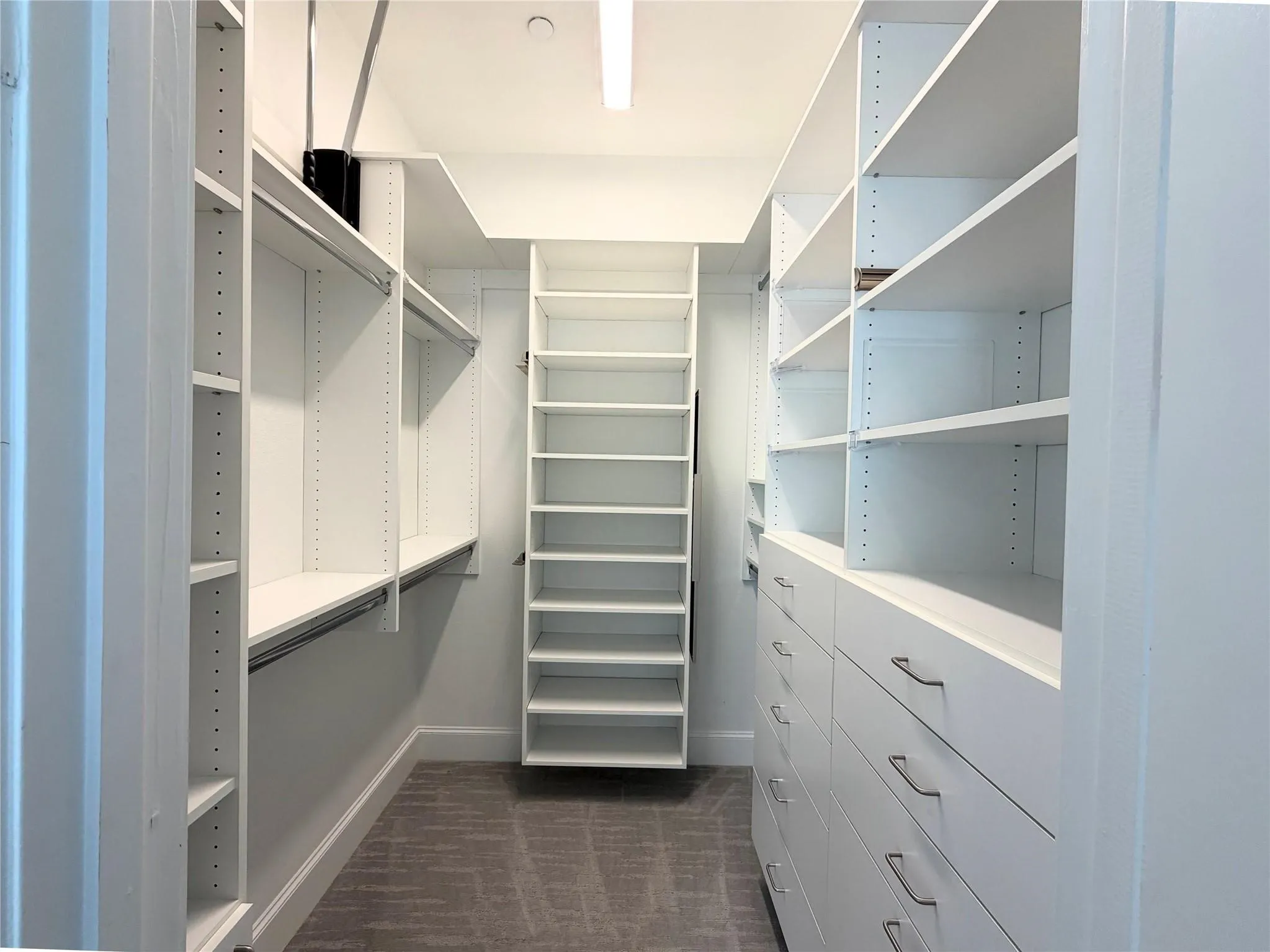 Expansive closet system featuring multiple shelving units, integrated hanging rods, extensive drawer storage with metal pulls, and a built-in ladder