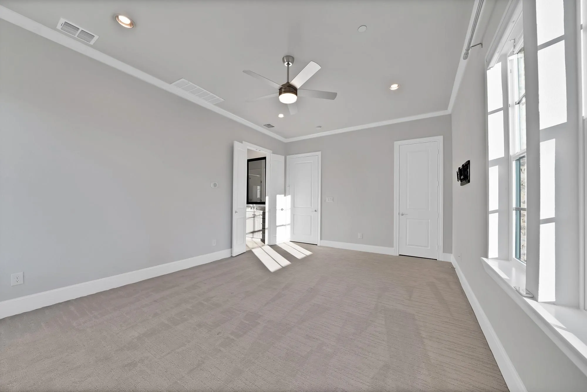 Spacious room featuring carpeting, recessed lighting, a ceiling fan, and multiple windows