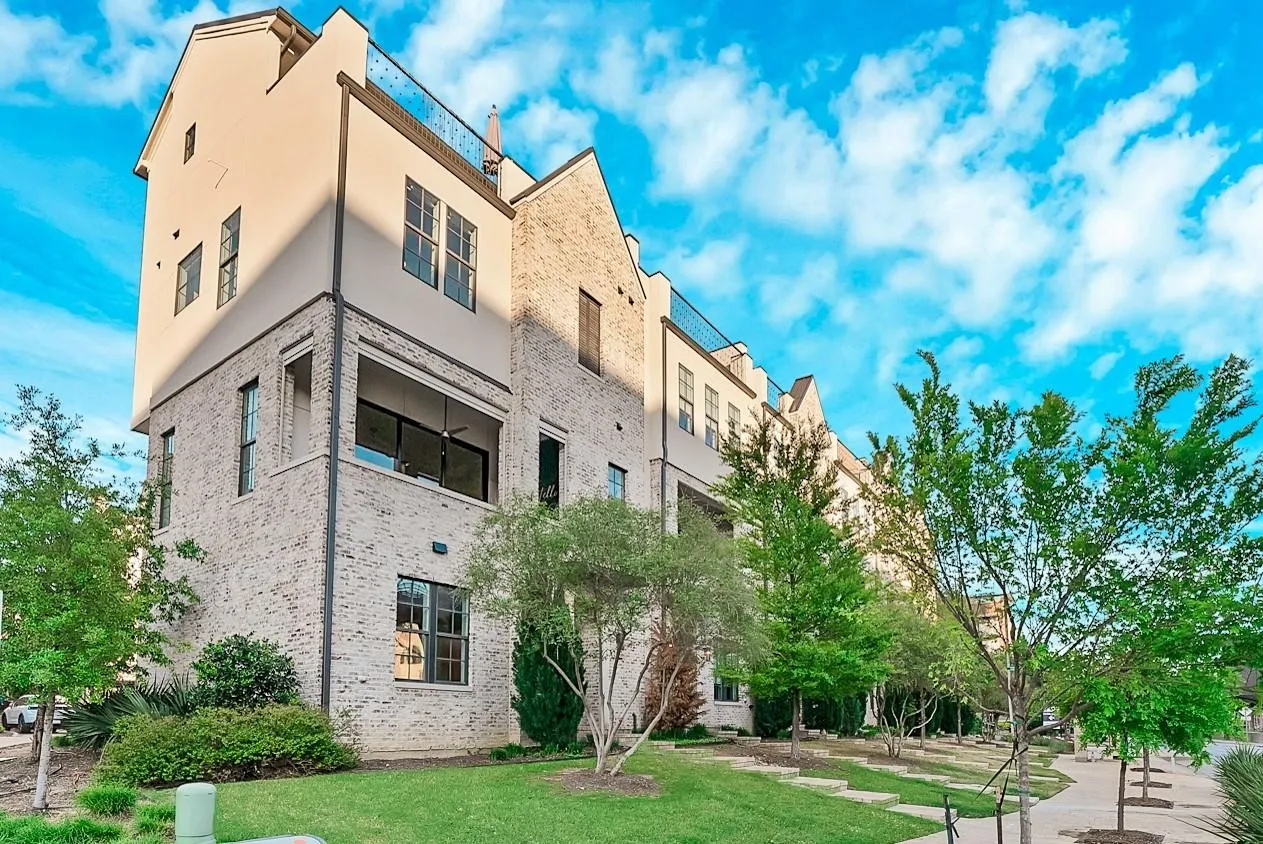 Multi-story exterior with brick and stucco cladding, featuring multiple windows, and an upper-level balcony with a sliding glass door
