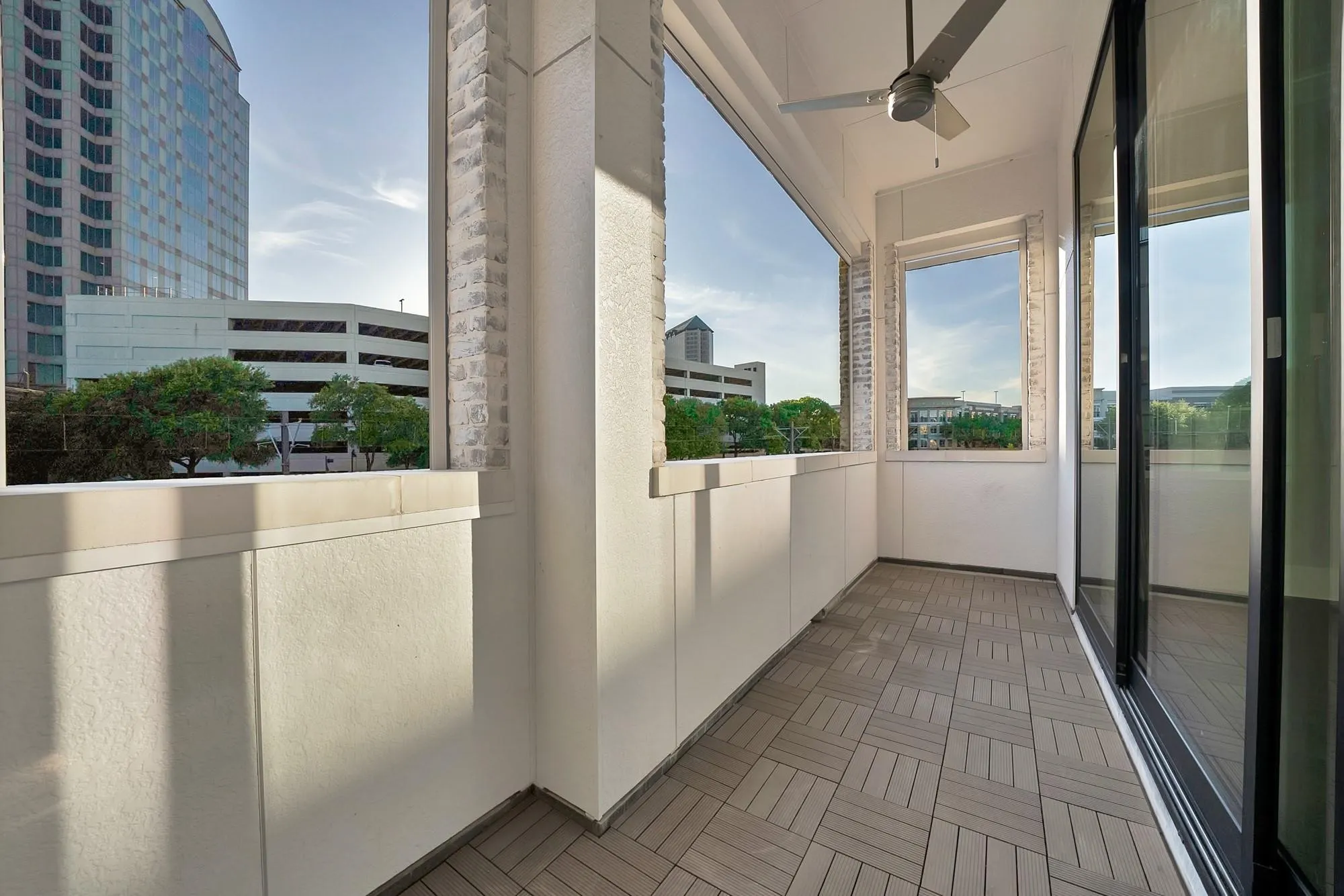 Outdoor balcony with patterned tile flooring, a ceiling fan, and sliding glass doors