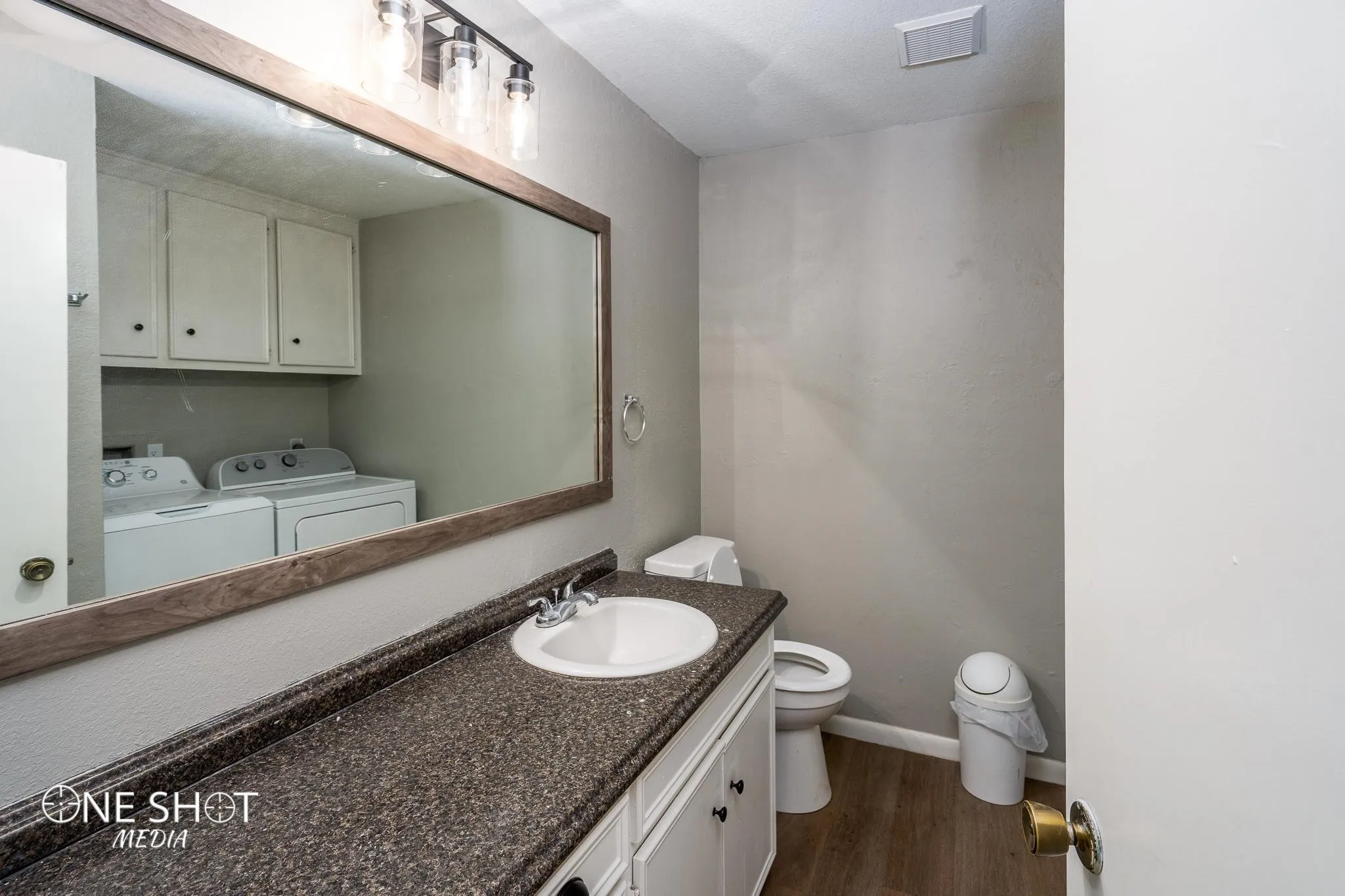 Bathroom featuring washing machine and clothes dryer, vanity, wood-type flooring, and toilet