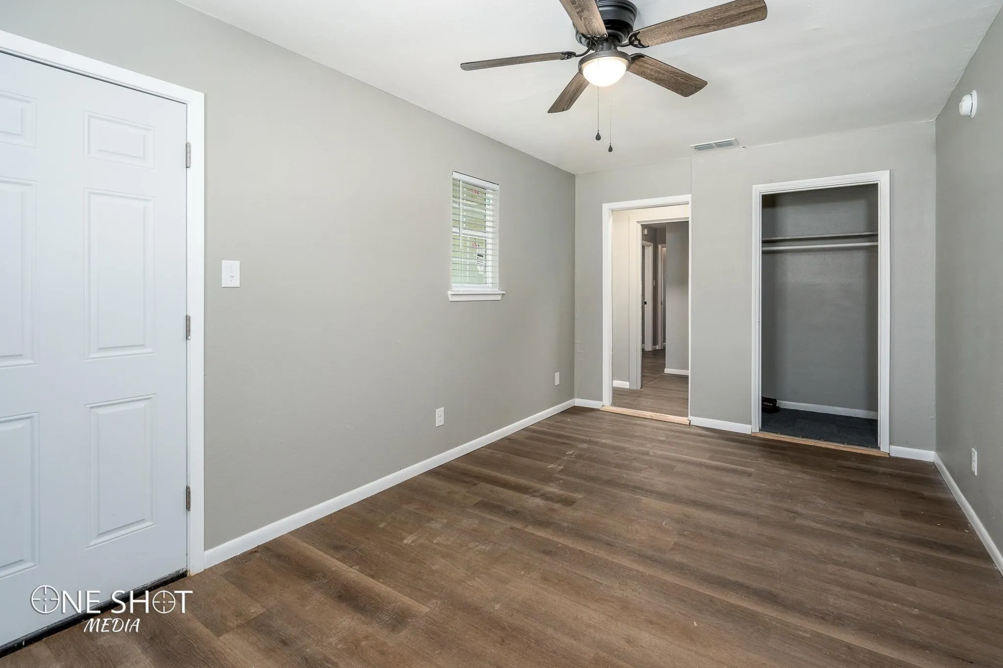 Unfurnished bedroom with ceiling fan, dark wood-type flooring, and two closets