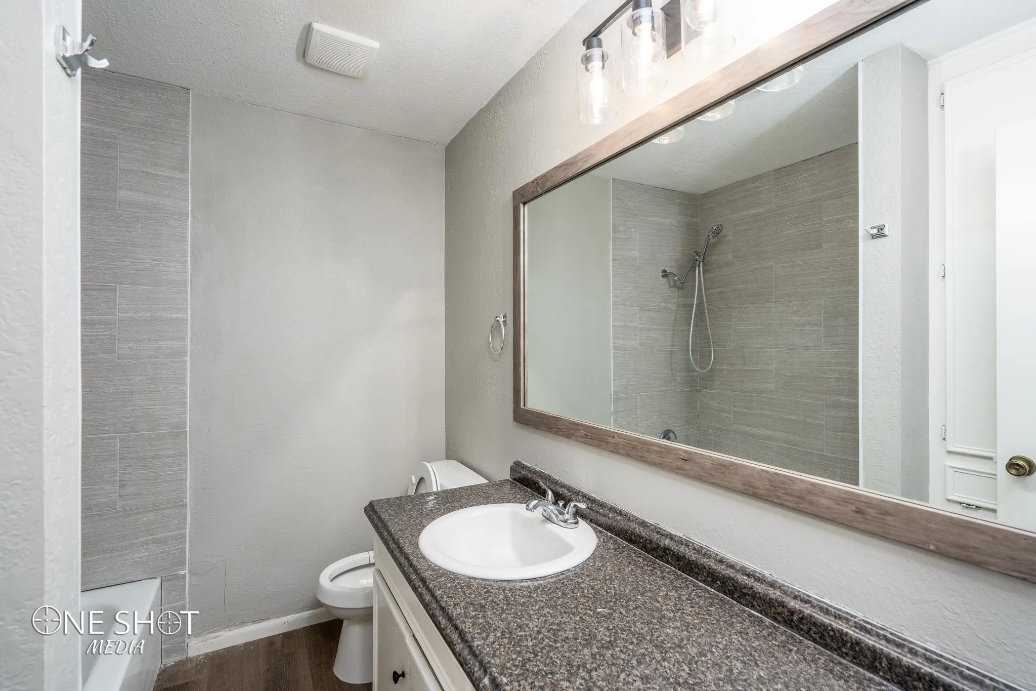 Bathroom featuring tiled shower, vanity, hardwood / wood-style flooring, and toilet