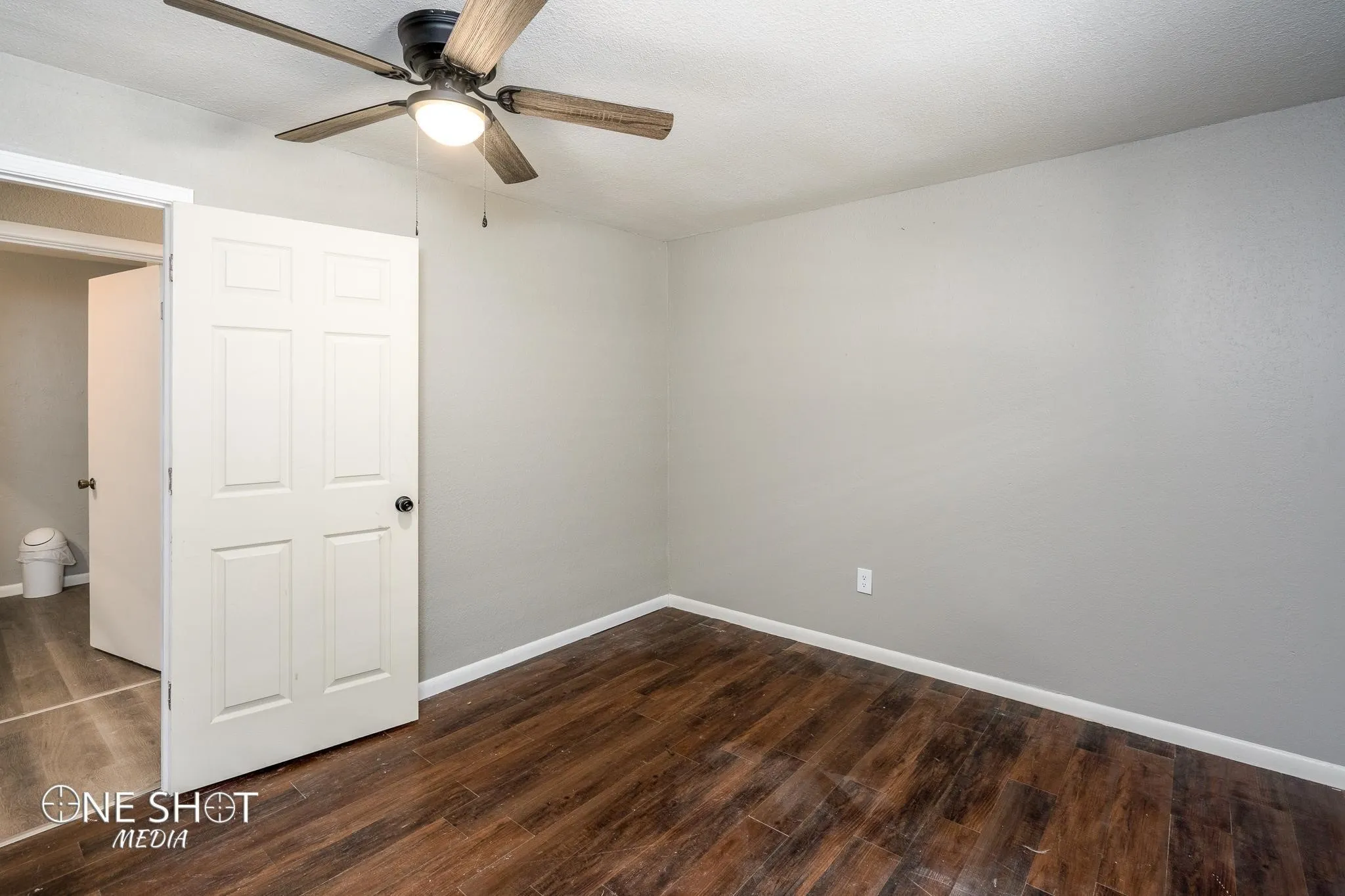 Empty room with ceiling fan, dark hardwood / wood-style flooring, and a textured ceiling