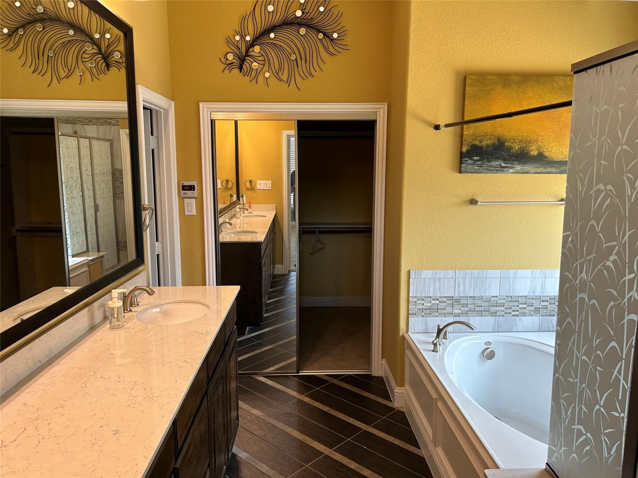 Full bath featuring vanity, a bath, a walk in closet, and inlaid floor details