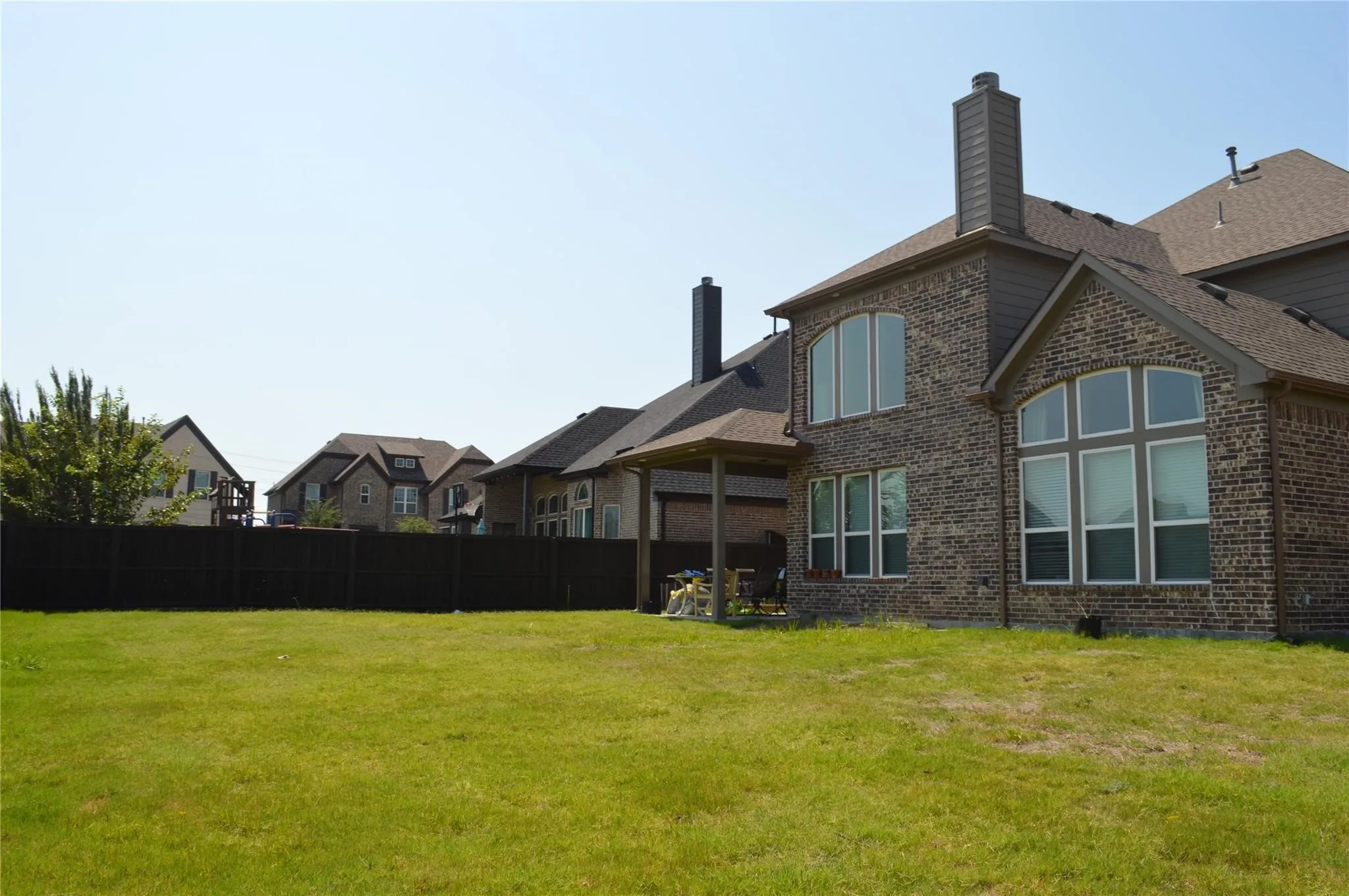 Back of house with a chimney, brick siding, and a shingled roof