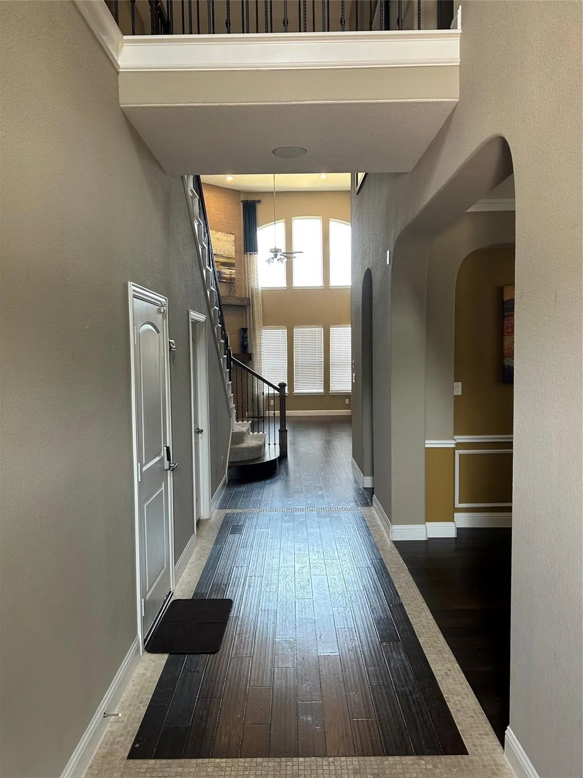 Hallway featuring a high ceiling, wood-type flooring, stairway, and arched walkways