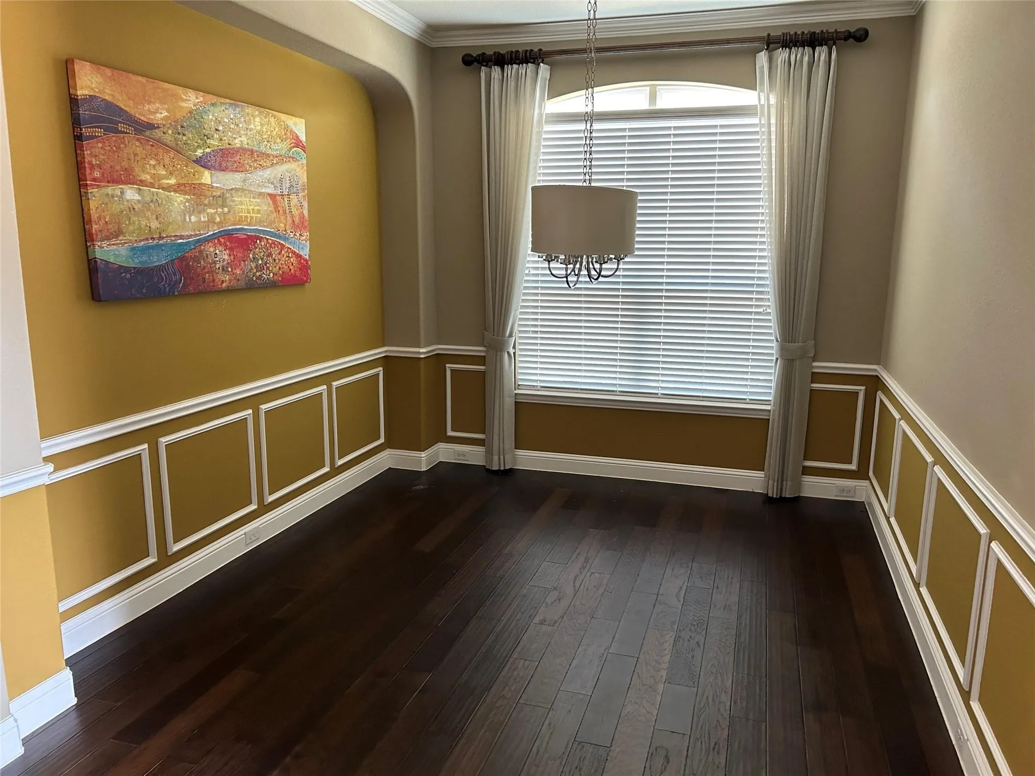 Unfurnished room with dark wood-style floors, a decorative wall, crown molding, and wainscoting