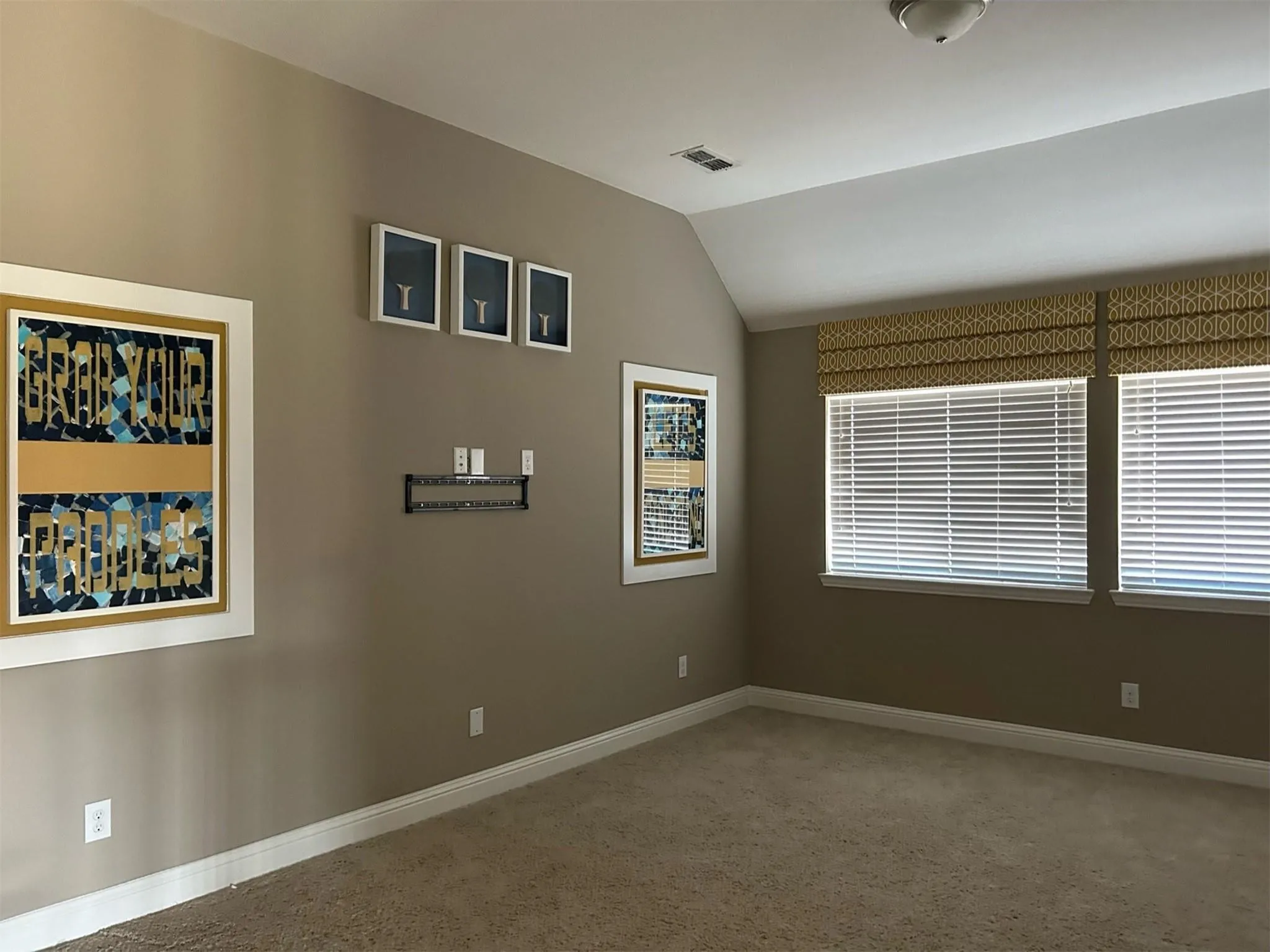 Carpeted spare room with baseboards and vaulted ceiling