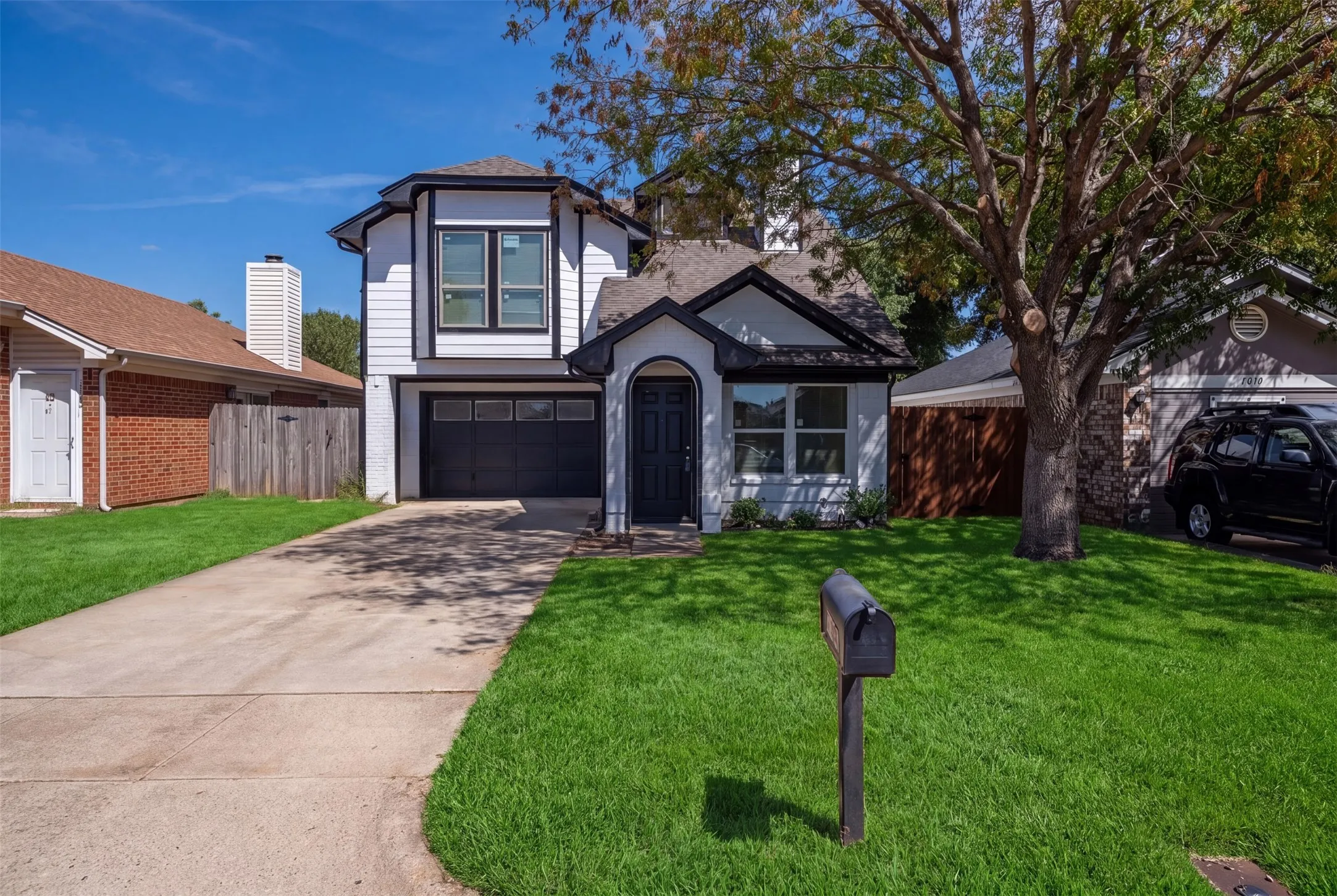 Two-story home with a black garage door and an arched entryway
