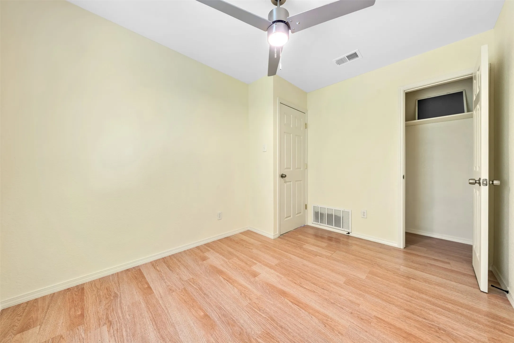 Wood-finish flooring, ceiling fan with integrated lighting, and a built-in closet with shelving