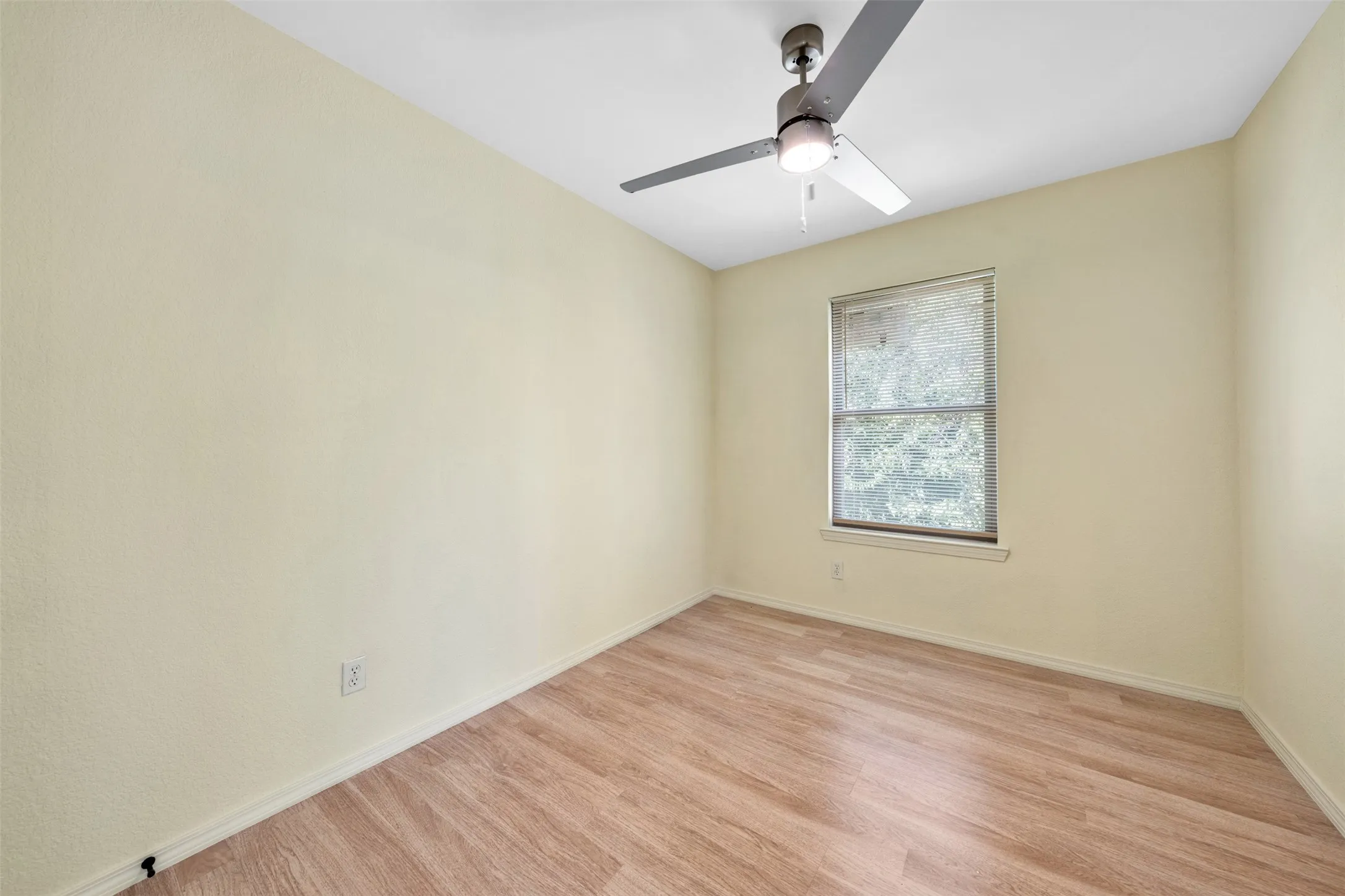 Wood-finish flooring, single window, and ceiling fan with integrated lighting