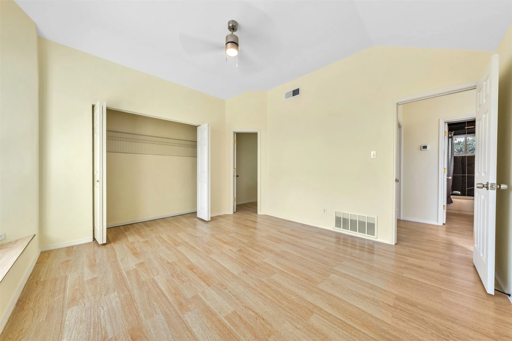 Vaulted ceiling, wood-finish flooring, ceiling fan with integrated lighting, bi-fold closet doors, and recessed lighting