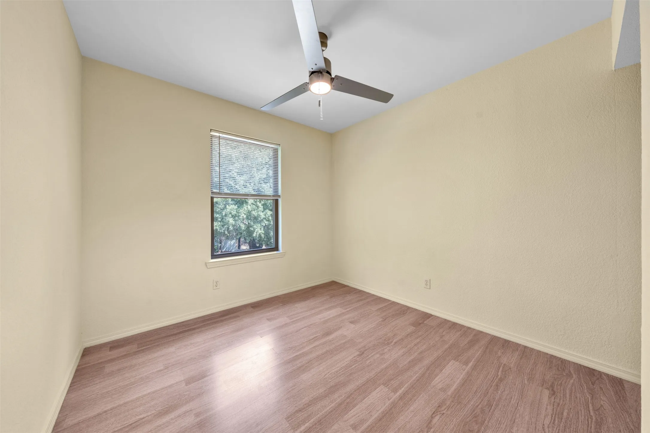 Recessed window with blinds, wood-finish flooring, and a ceiling fan with integrated lighting