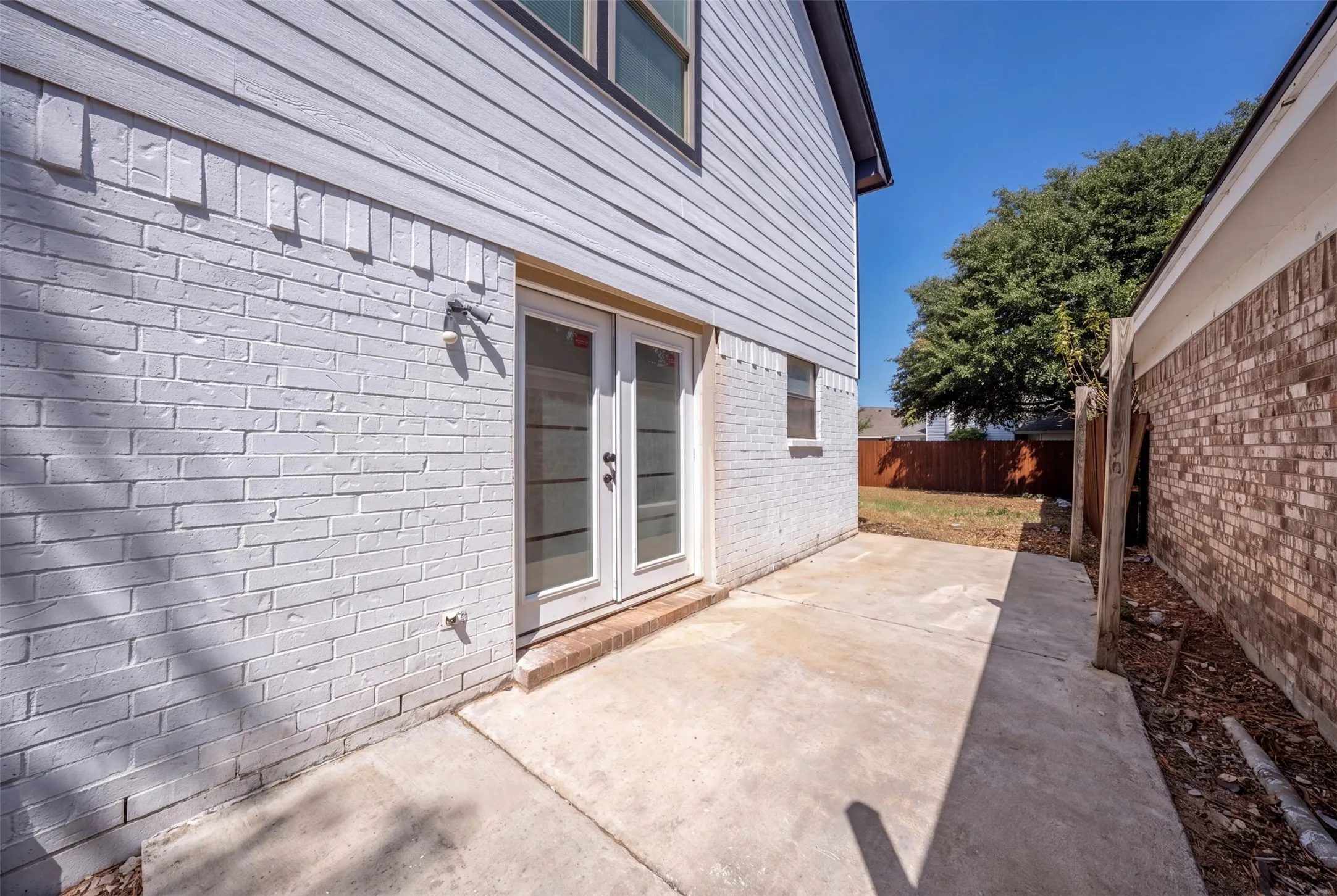 White brick exterior with horizontal siding, a concrete patio, and a double-door entry