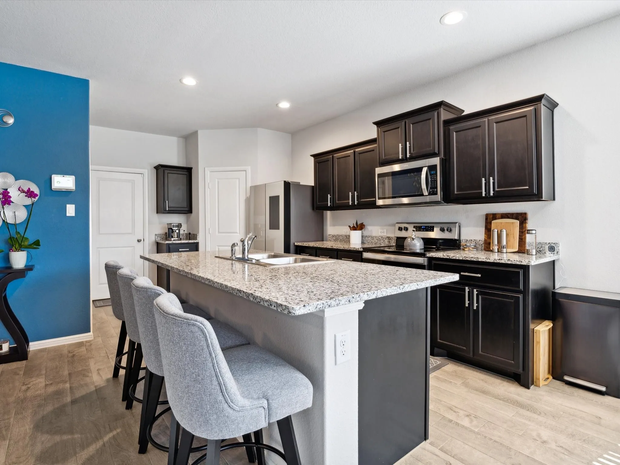 Kitchen featuring an island with stone countertops, dark wood-finish cabinetry, stainless steel appliances, and recessed lighting
