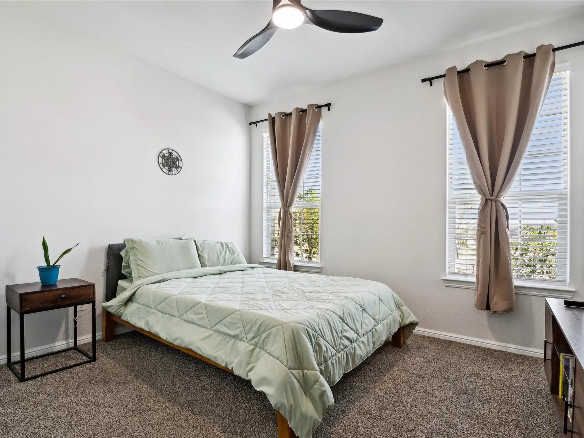 Carpeted room featuring a ceiling fan with integrated lighting, two windows with blinds, and a built-in wall decor piece