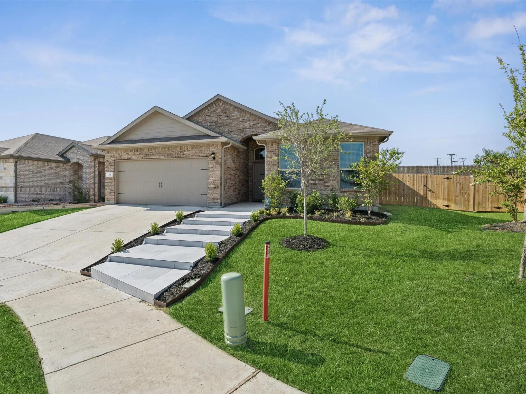 Brick exterior with a gabled roofline, concrete driveway, and attached two-car garage