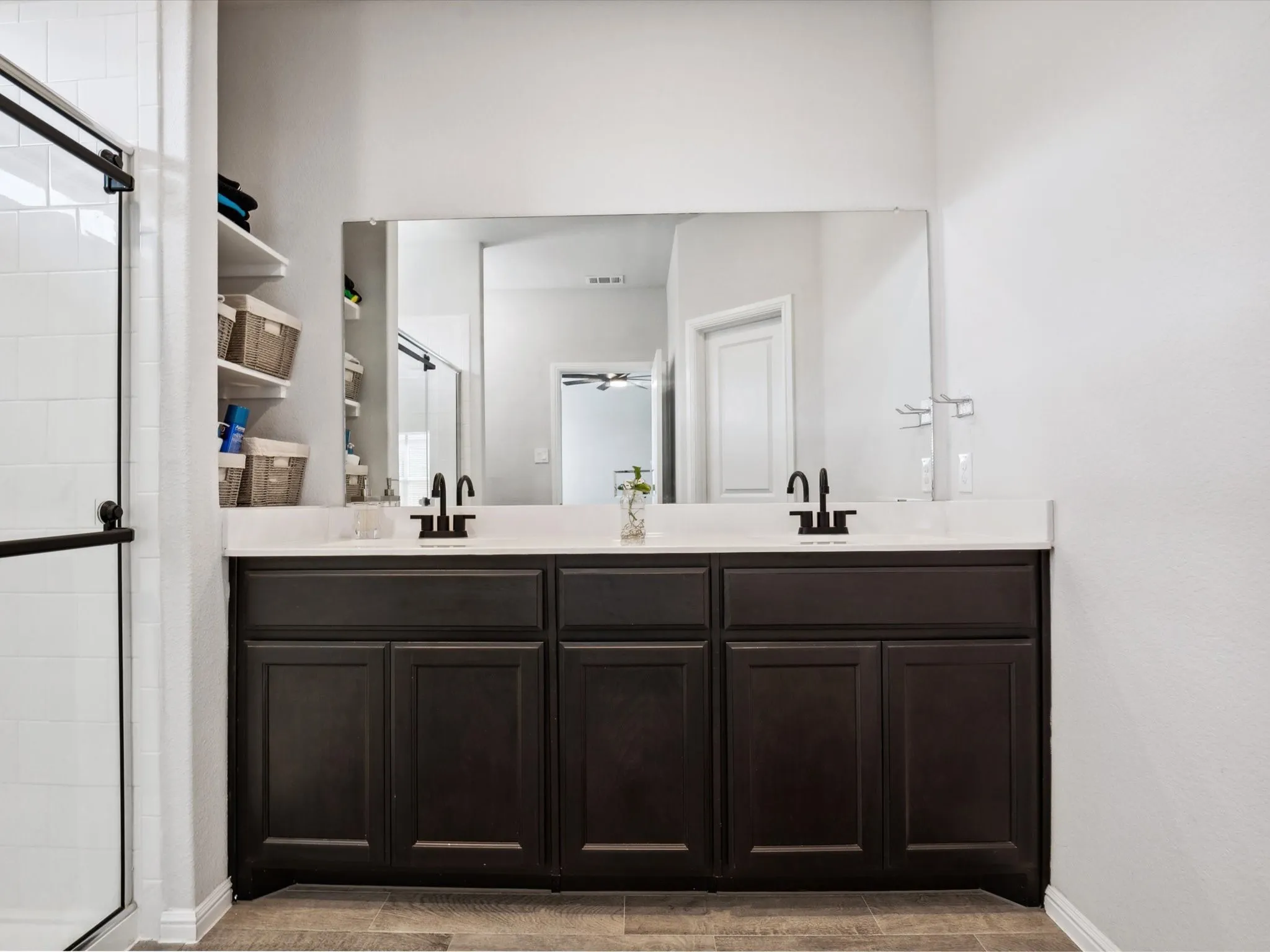 Dual vanity with dark wood-finish cabinetry, light-toned countertop, and matte black fixtures