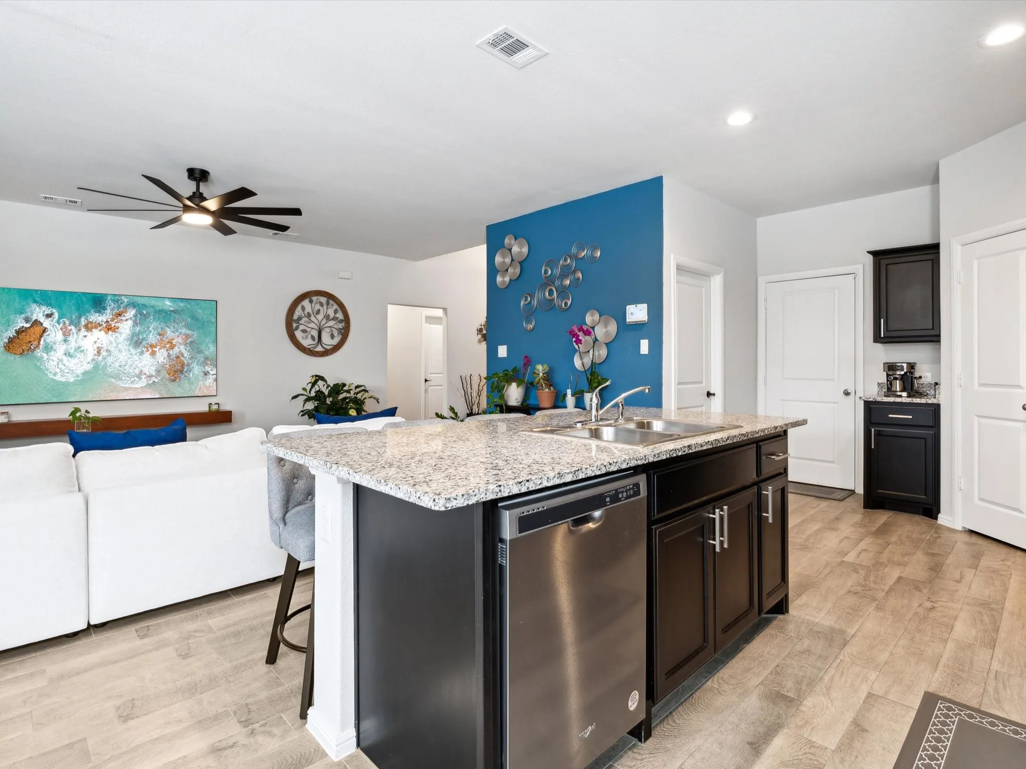 Kitchen island featuring a double-basin sink, stainless steel dishwasher, and light-toned granite-finish countertop