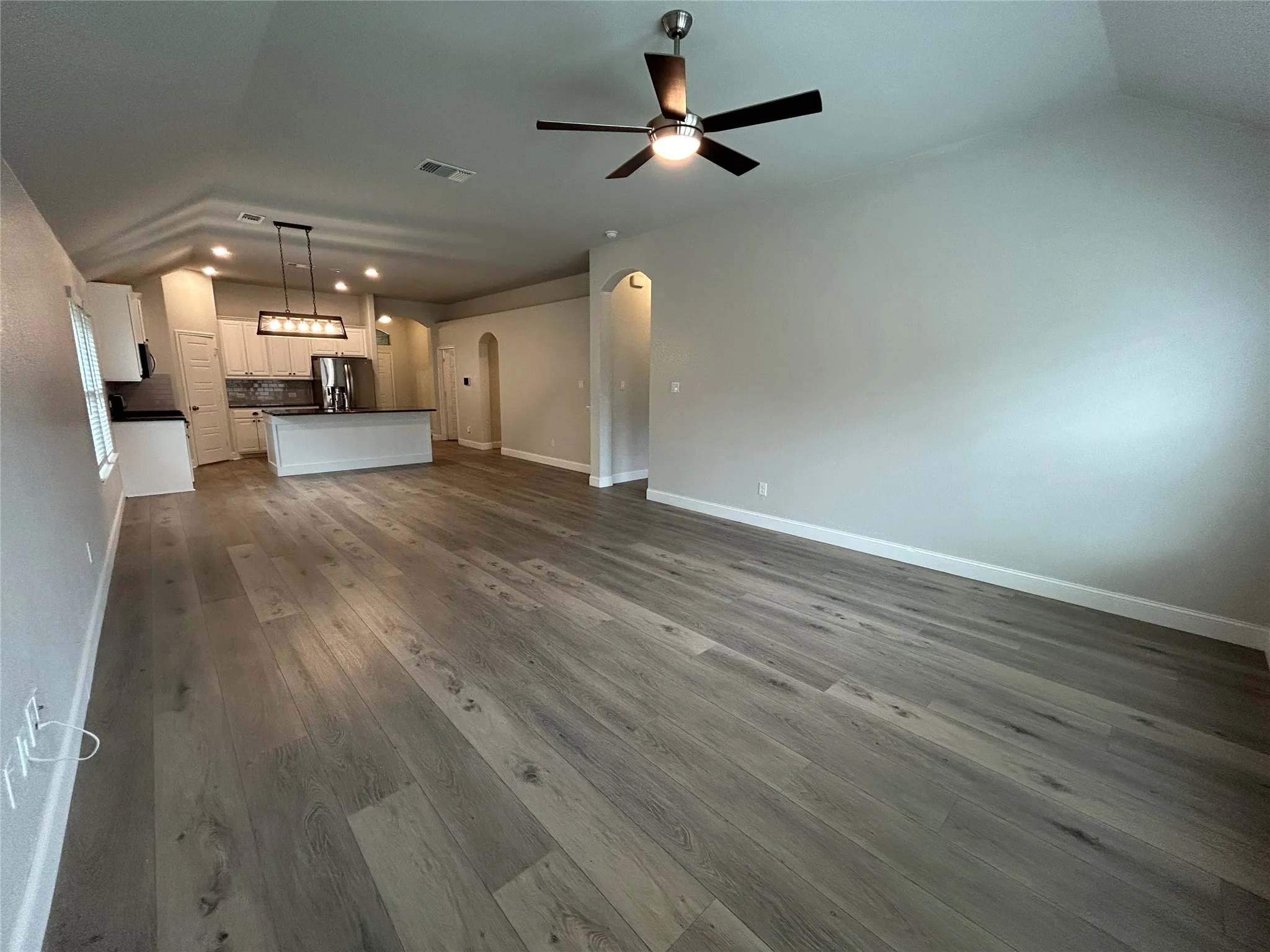 Vaulted ceiling, wood-finish flooring, recessed lighting, ceiling fan, and arched doorways