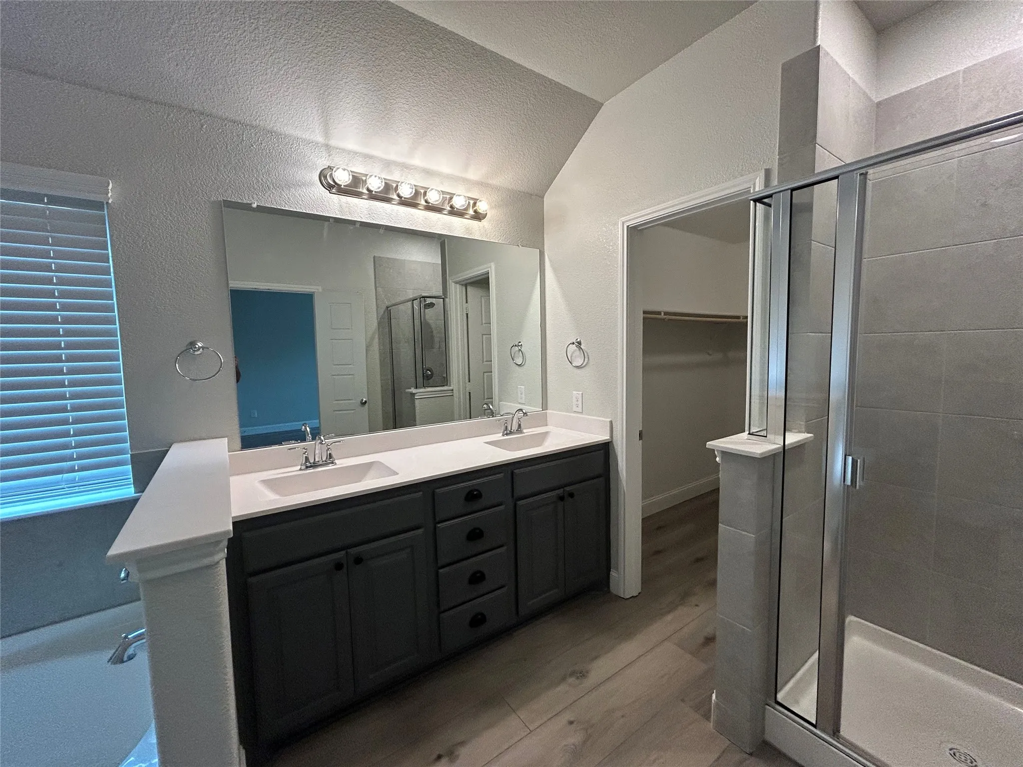 Dual vanity with dark cabinetry, integrated sinks, and a large mirror