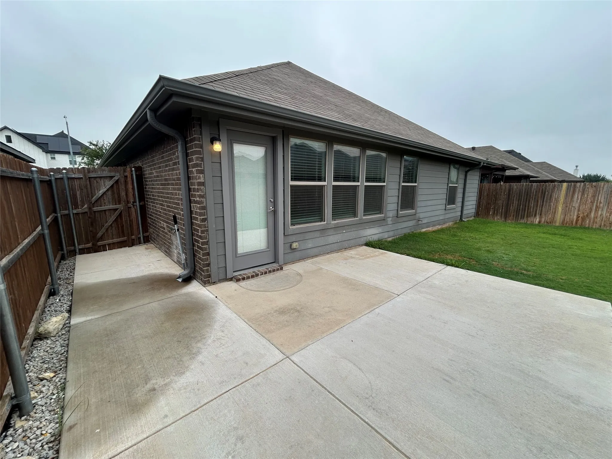 Private fenced yard featuring a concrete patio, a grass lawn, and a side access gate