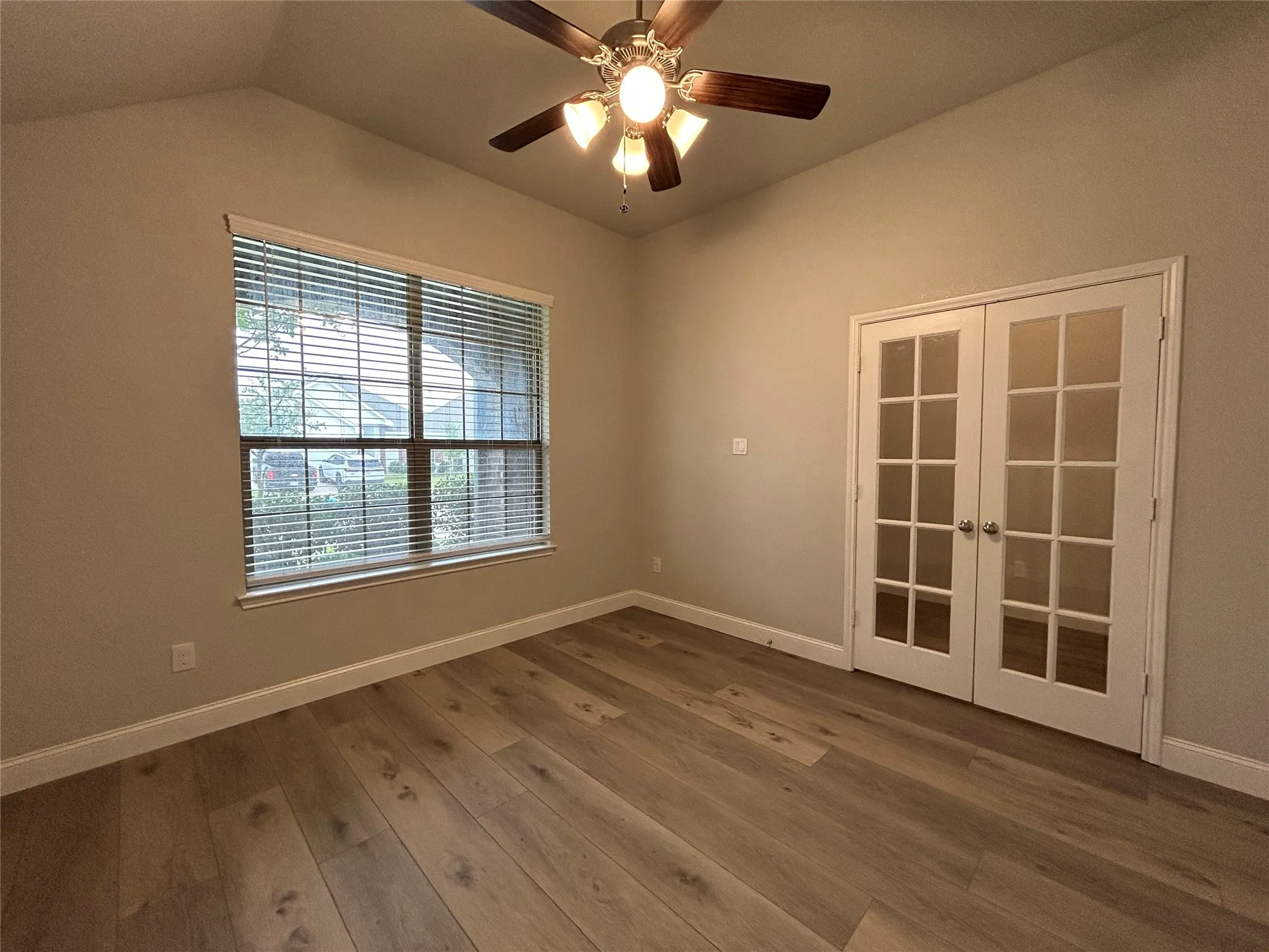 Vaulted ceiling with a ceiling fan, wood-finish flooring, and French doors
