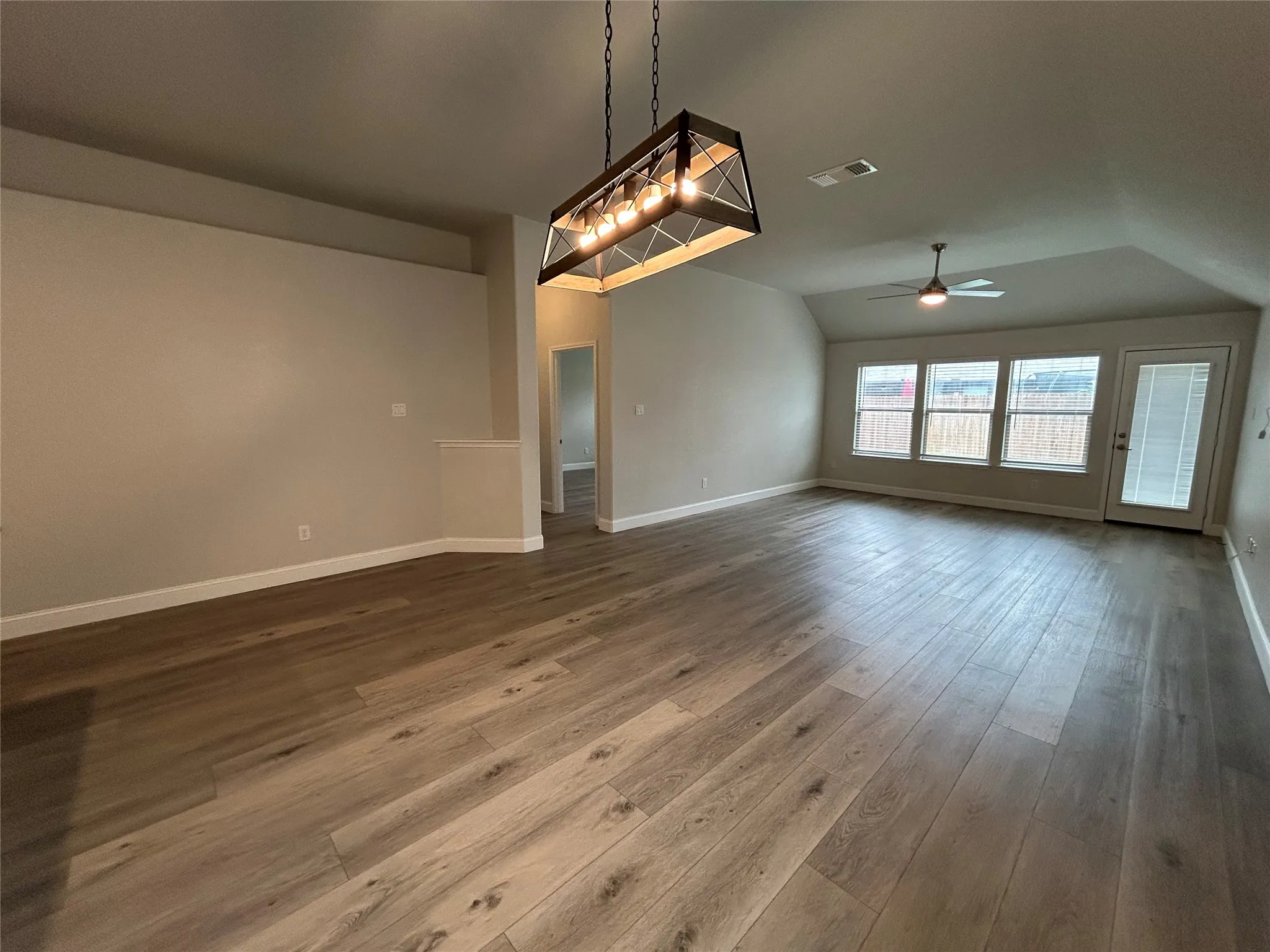 Wood-finish flooring throughout, vaulted ceiling, multi-pane windows, and a glass-paneled exterior door