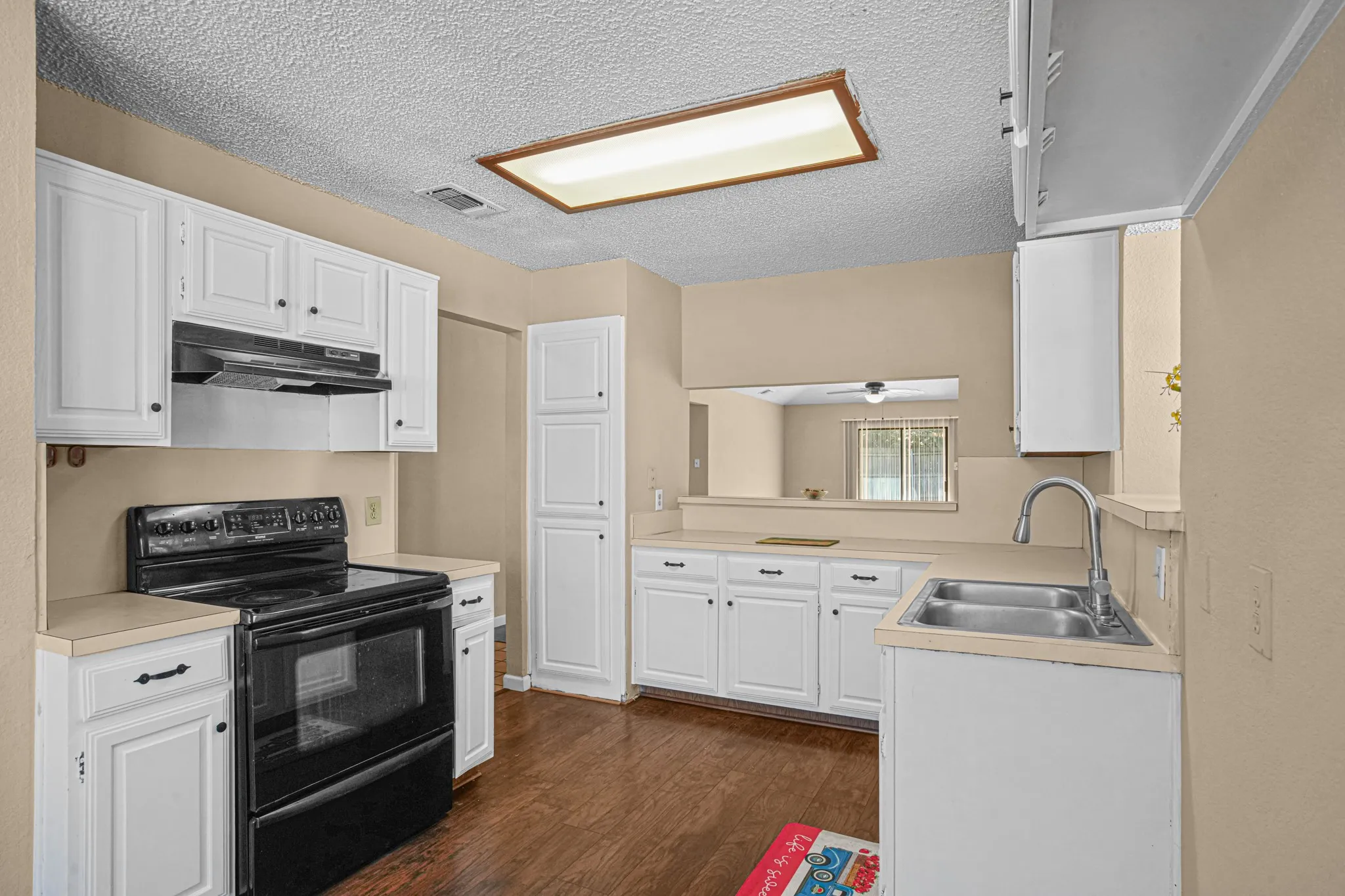 Kitchen has apple suppy of cabinets, electric freestanding stove. A opening to stay engarged while cooking a meal.