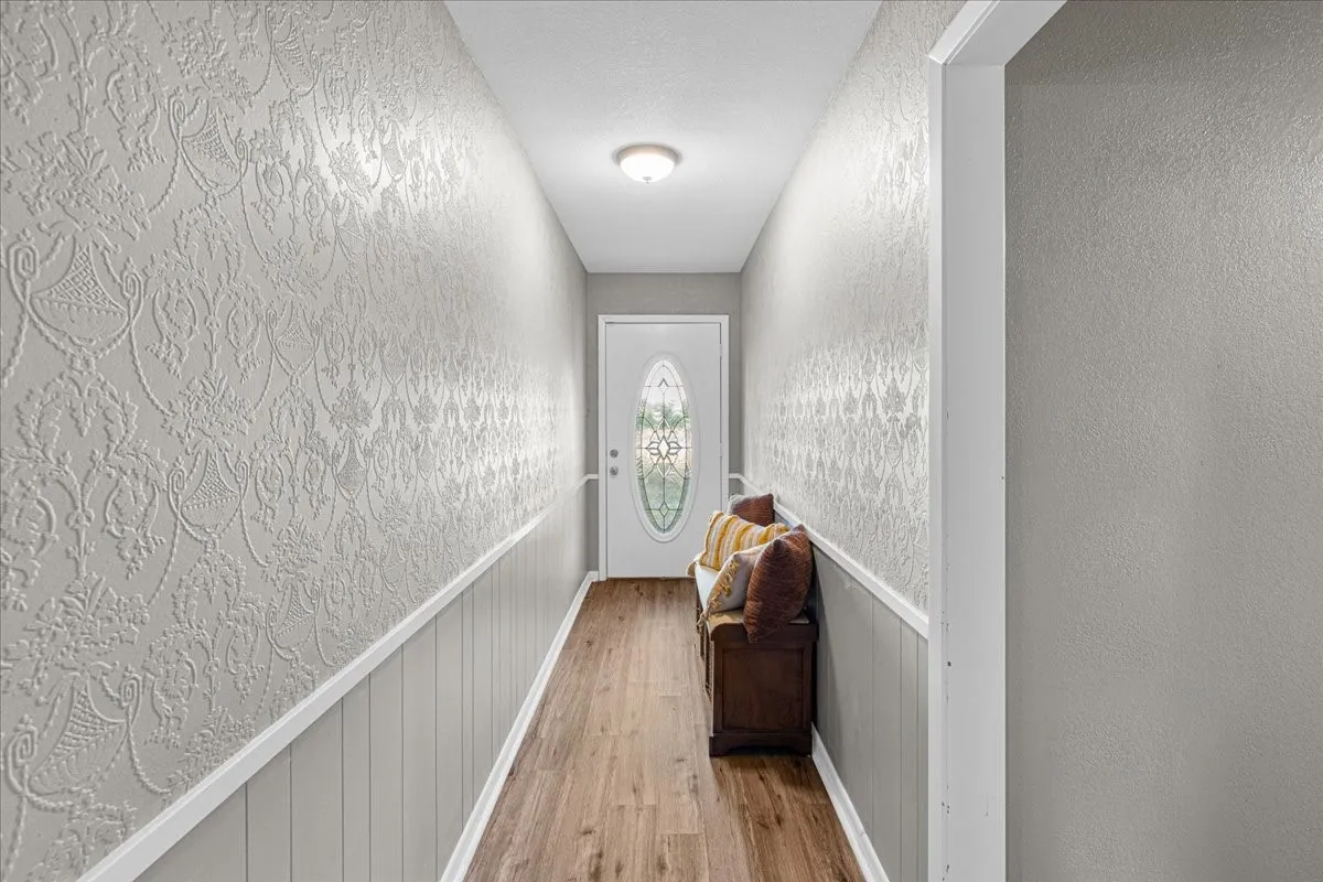 Wood-finish flooring leading to an oval-glass front door