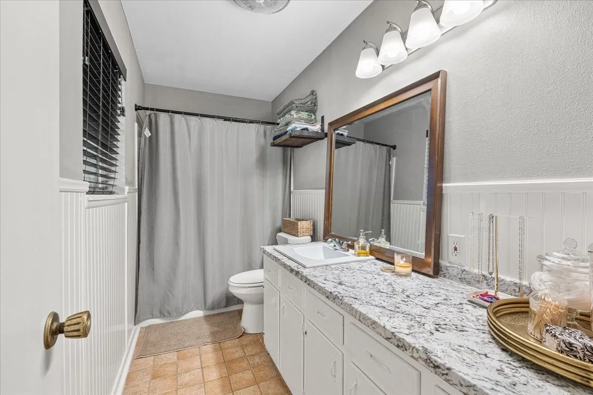 White vanity with integrated sink, speckled countertop, and wood-framed mirror