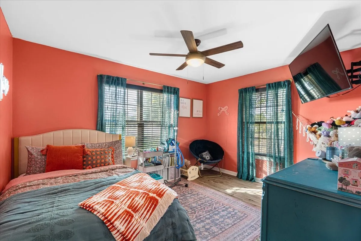 Ceiling fan with integrated lighting, wood-finish flooring, and window blinds