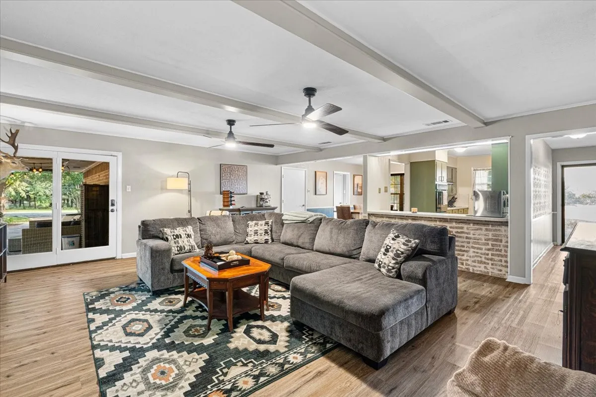 Beamed ceiling, wood-finish flooring, sliding glass patio doors, breakfast bar with brick detail, and recessed lighting