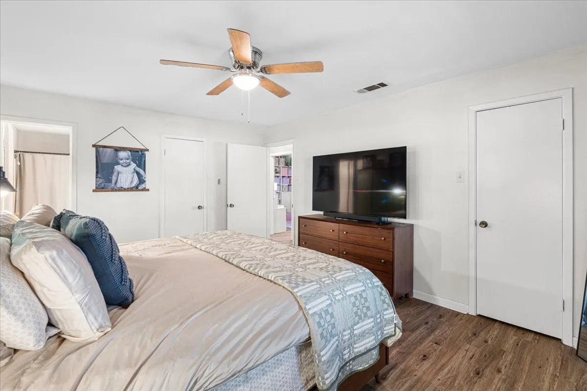 Wood-finish flooring with white walls and a ceiling fan