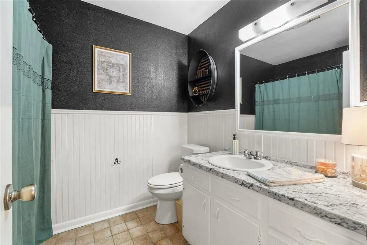 Vanity with integrated sink, stone-finish countertop, and white cabinetry