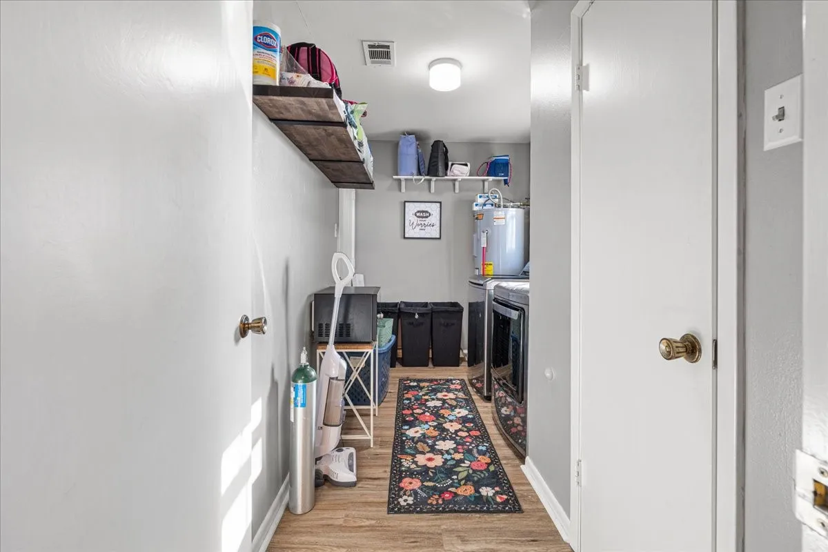 Utility area featuring wood-finish flooring, built-in shelving, and a water heater