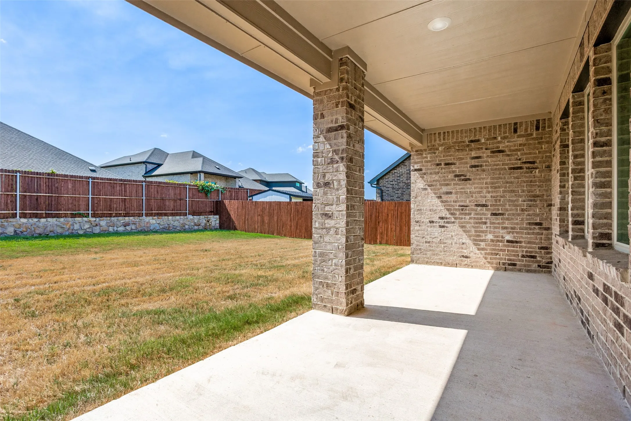 Covered patio with brick columns, recessed lighting, and a concrete surface