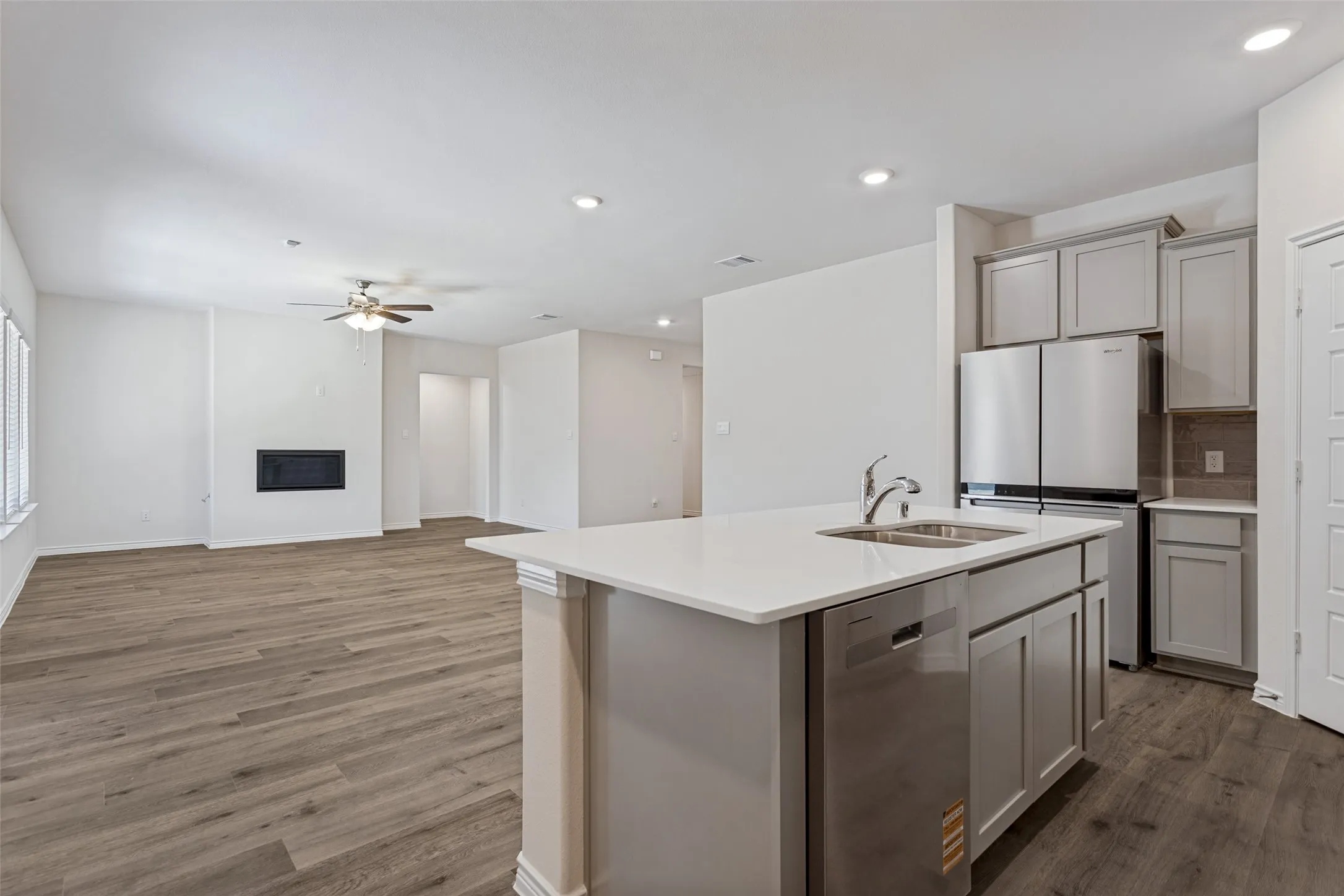 Open-concept living space featuring wood-finish flooring, recessed lighting, and a built-in fireplace