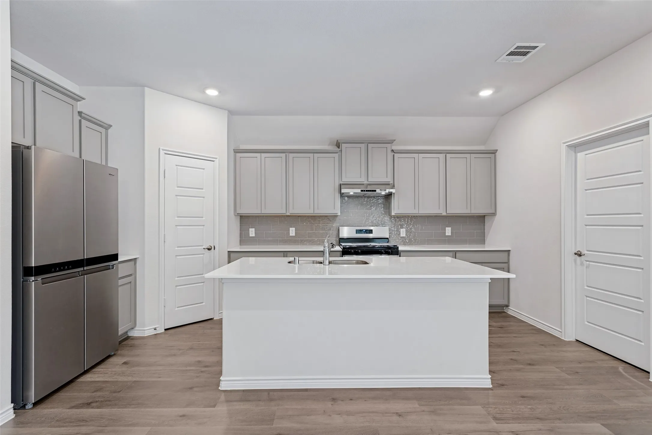 Kitchen featuring a large island, wood-finish flooring, recessed lighting, gray cabinetry, and stainless steel appliances