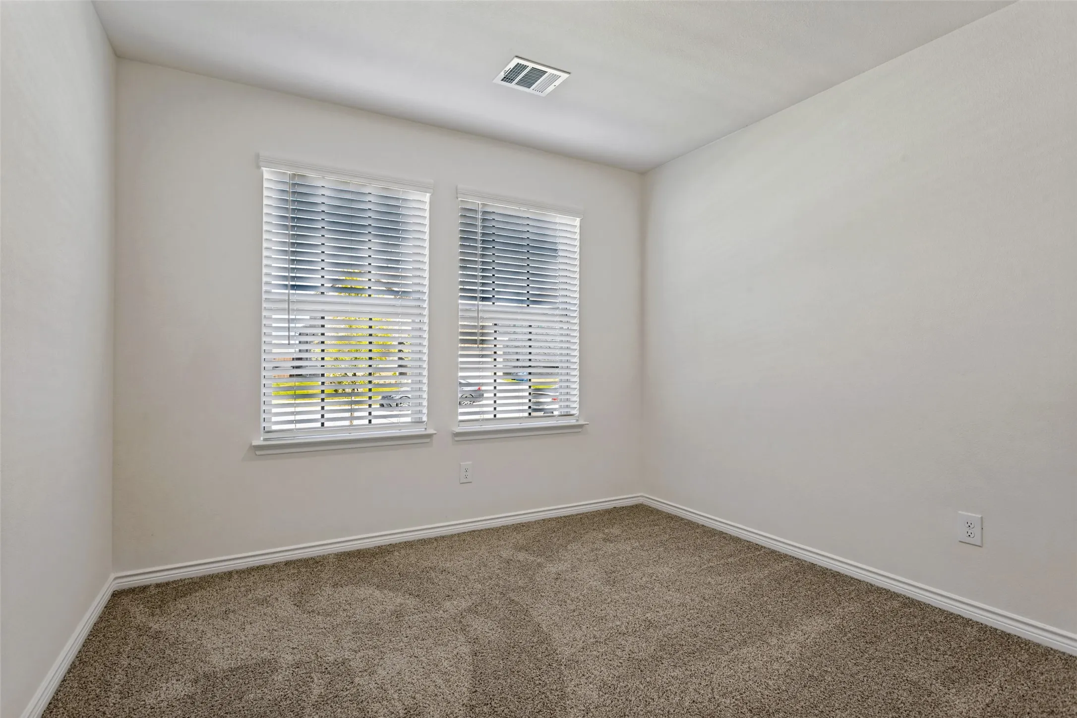Neutral wall color with carpet flooring and dual windows