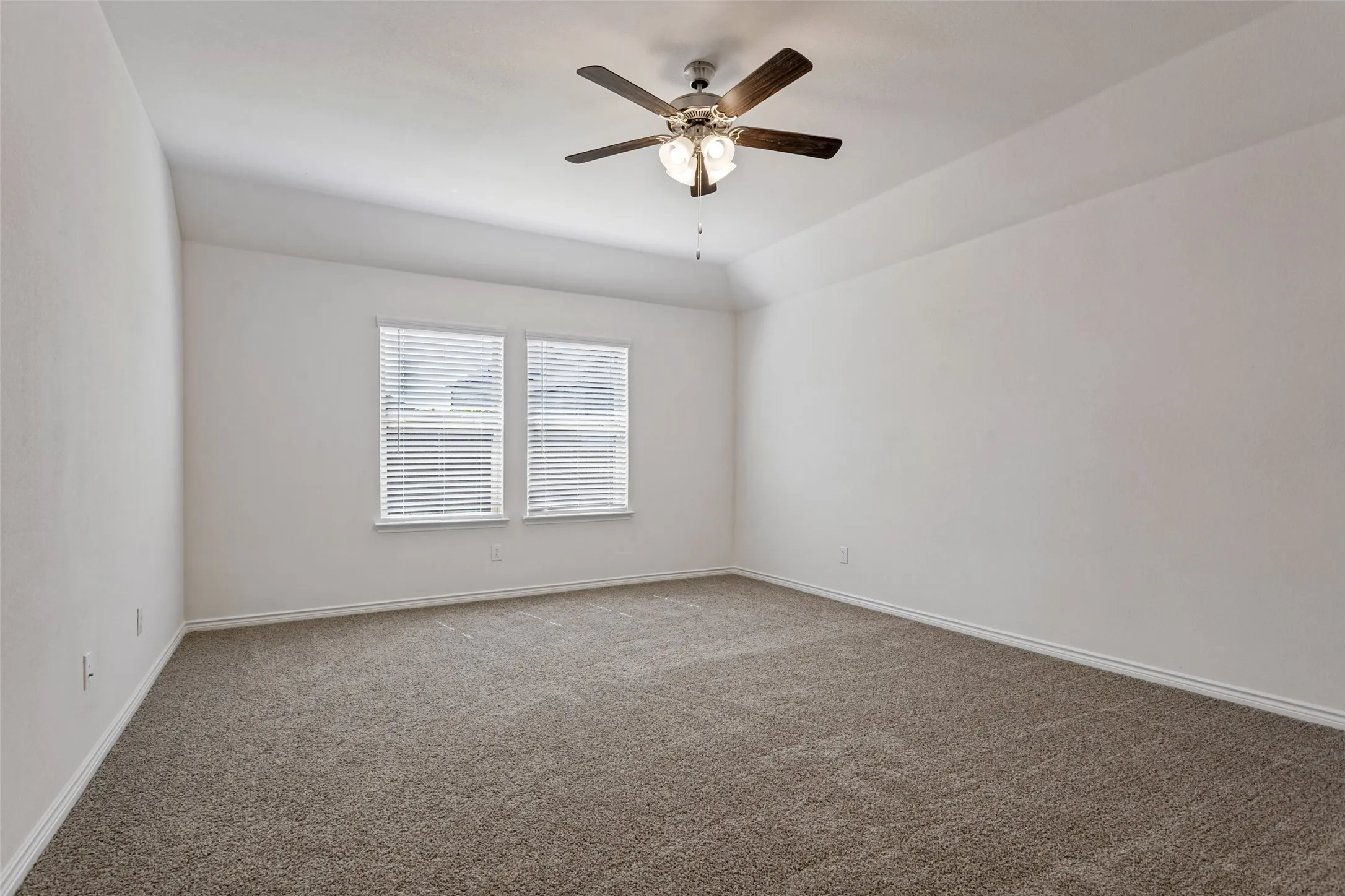 Carpeted interior space with a ceiling fan, dual windows, and white window blinds