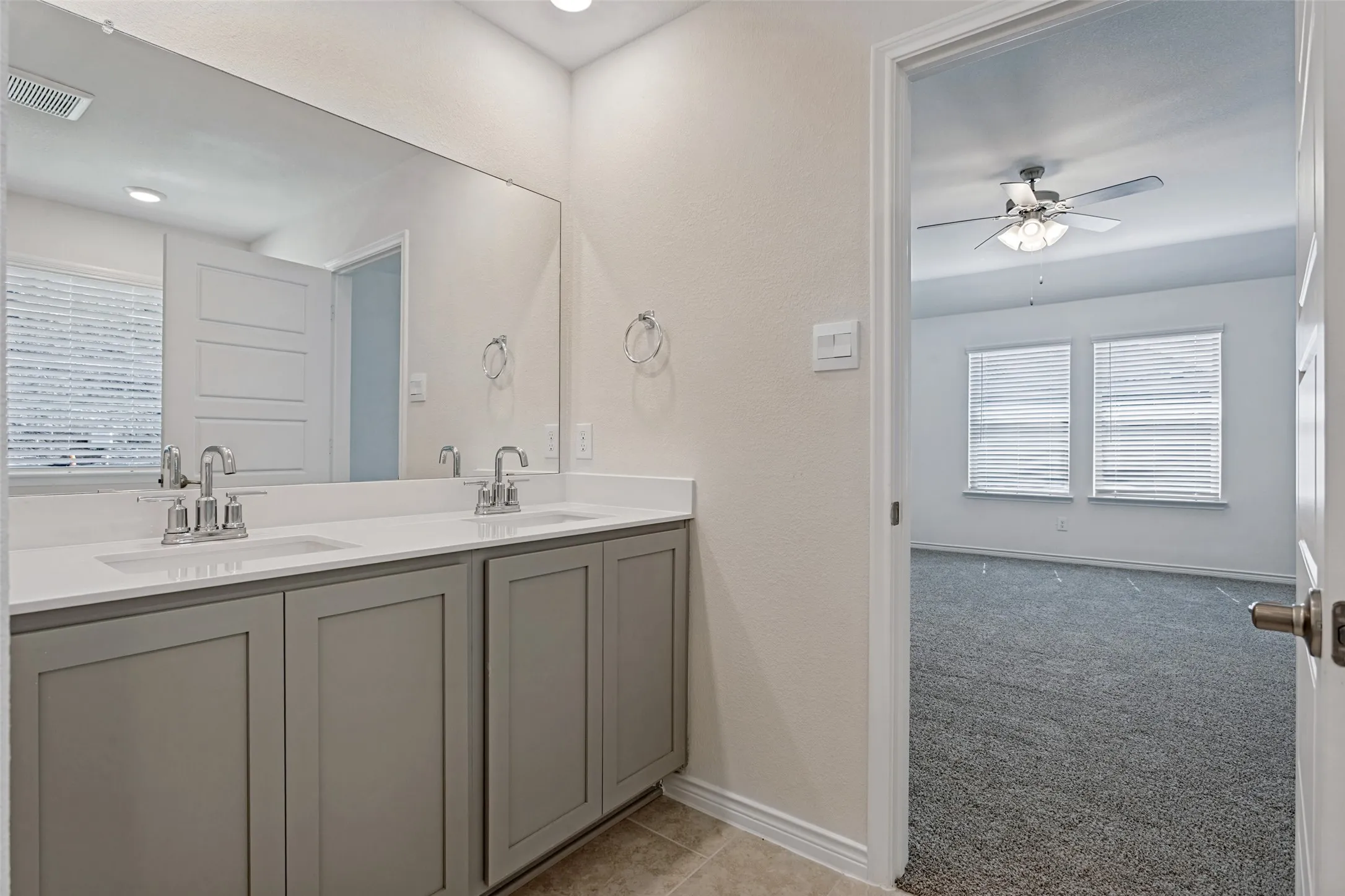 Dual vanity with undermount sinks and chrome fixtures, ample cabinetry, and an expansive mirror