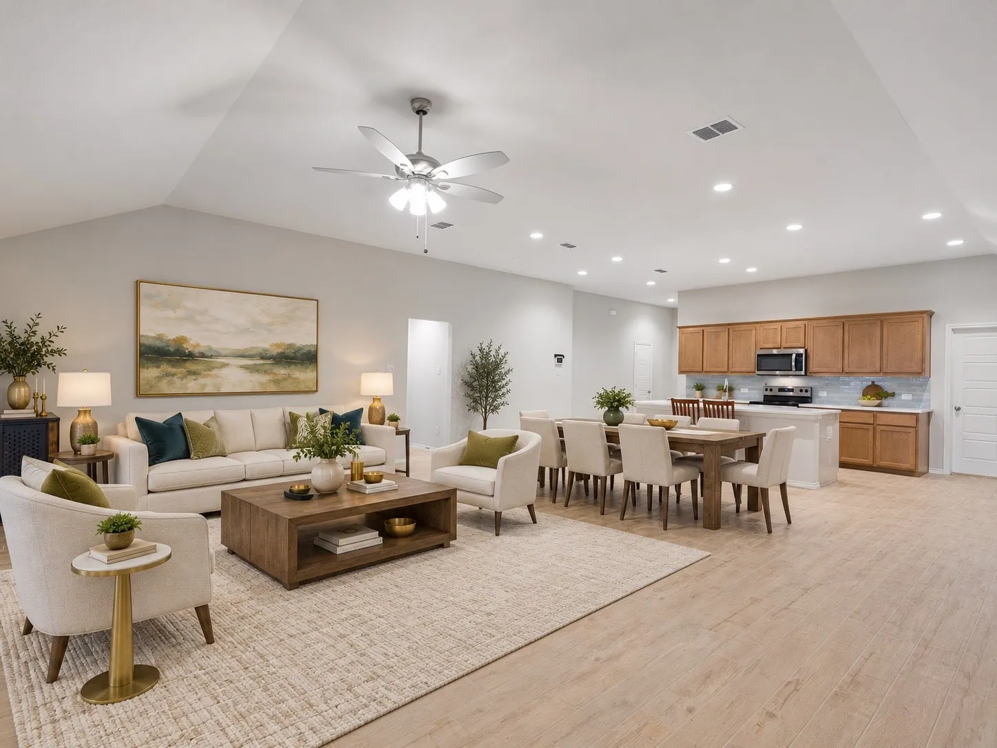 Vaulted ceiling with a ceiling fan, light wood-finish flooring, recessed lighting, and a kitchen with wood cabinetry, stainless steel appliances, and a tiled backsplash