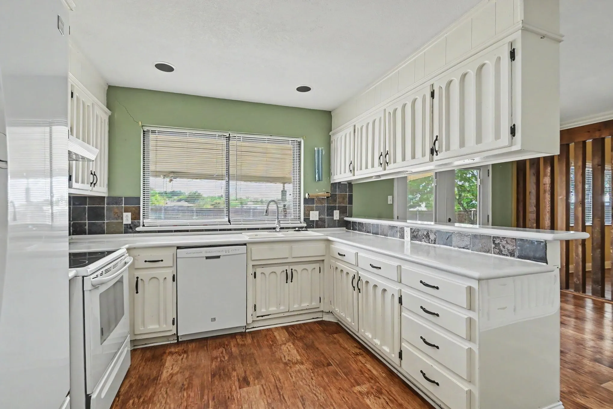 Kitchen featuring white cabinetry, a built-in dishwasher, and a stainless steel sink with a gooseneck faucet